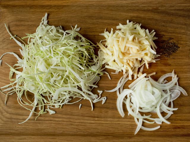 Snitt kålen i tynne strimler, ikke bruk den tykke midtstilken. Skjær løken i tynne skiver, skrell eplene og del dem i båter. Legg kål, løk, epler, karve og salt lagvis i en passende kjele.