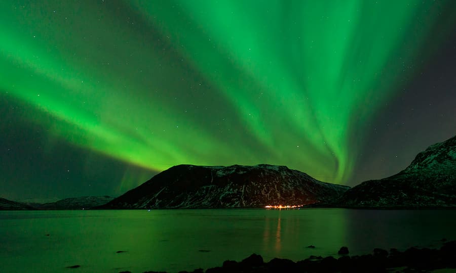 Tromsø badet i grønt nordlys i nattemørket