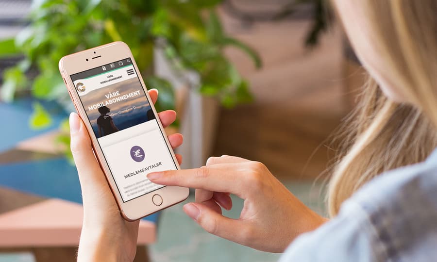 Dame som sitter på mobiltelefonen sin og surfer på Gudbrandsdal Energi sin hjemmeside