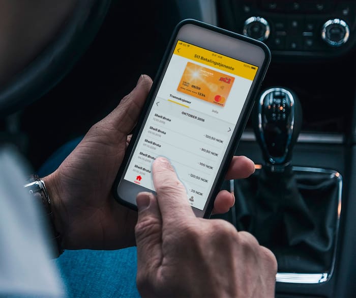 Sjåfør som sitter i bilen oh holder en telefon med bilde av Snarveien-appen