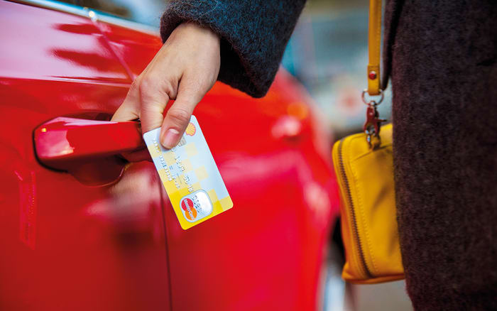Hånd som holder i Shell MasterCard mens den åpner en rød bildør