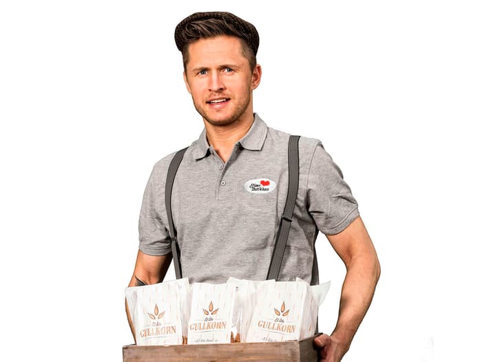 Ung mann i lederhosen som holder et brett med Gullkorn-brød