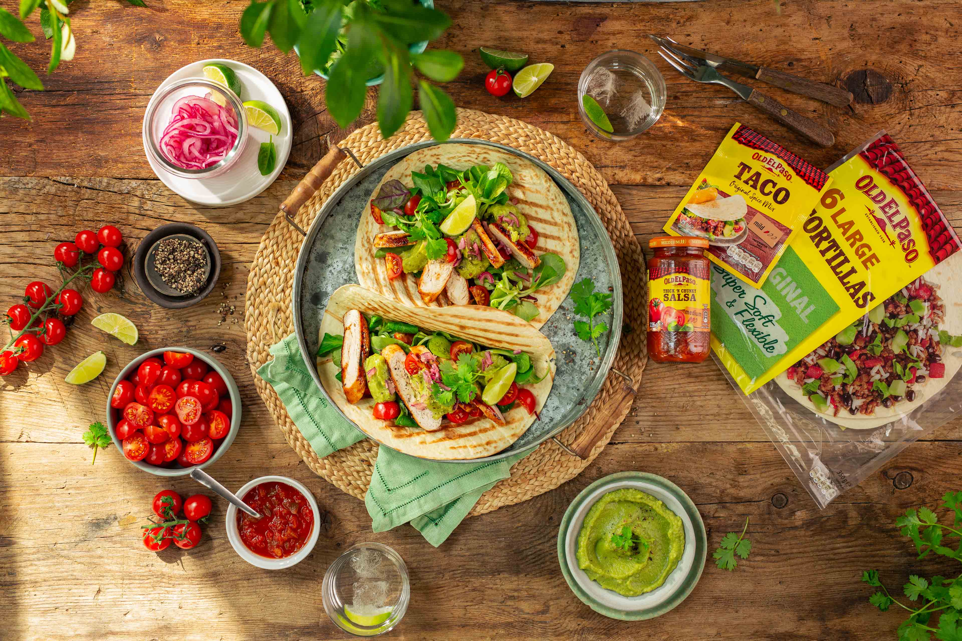 Grillet kyllingtaco på bord med tilbehør.