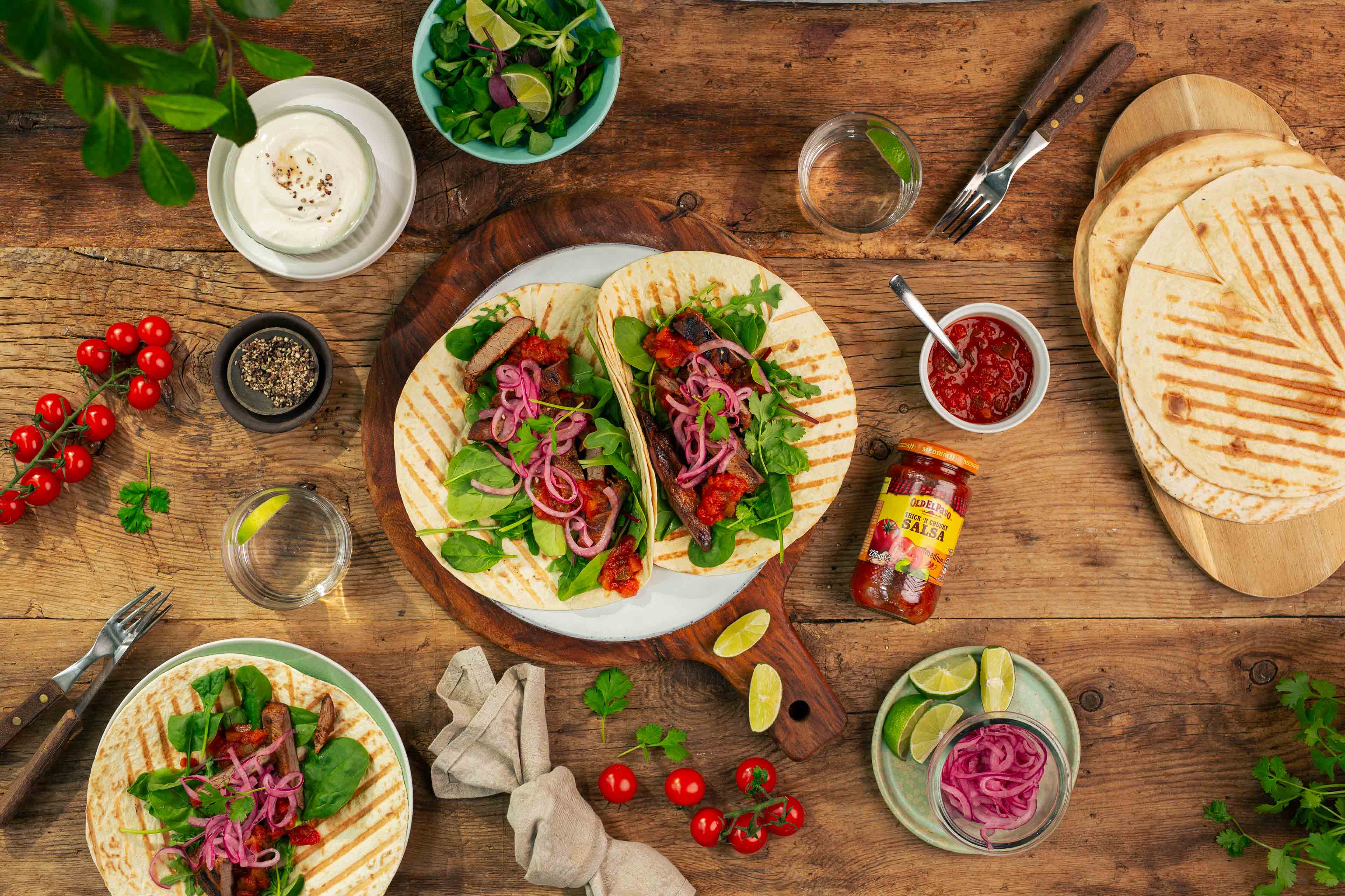 Grillet bifftaco på bord med tilbehør.