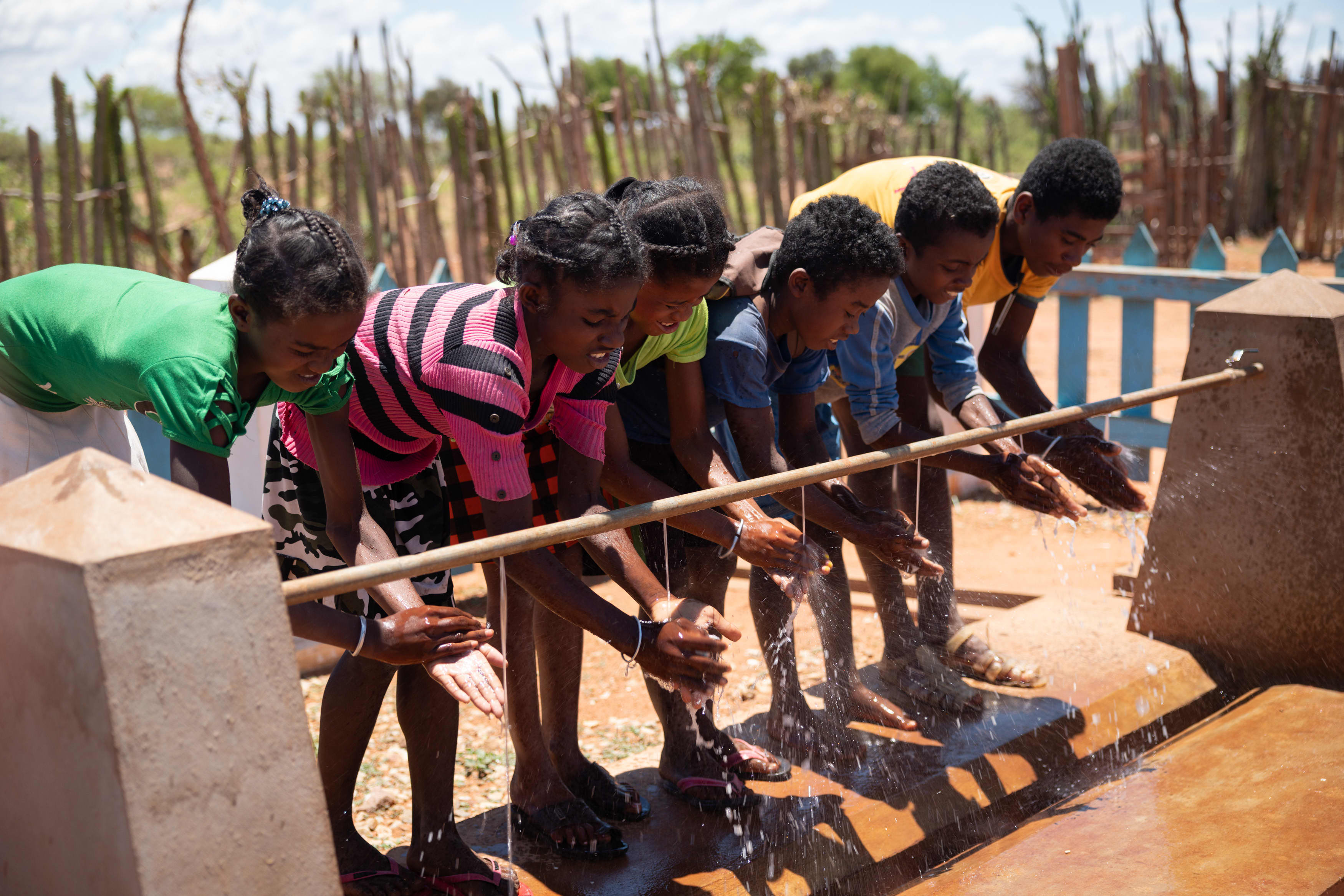 Seks barn i Madagaskar holder hendene under en vannkran