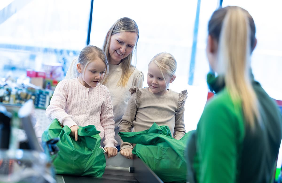 Mor som pakker varer i handlenett med to døtre