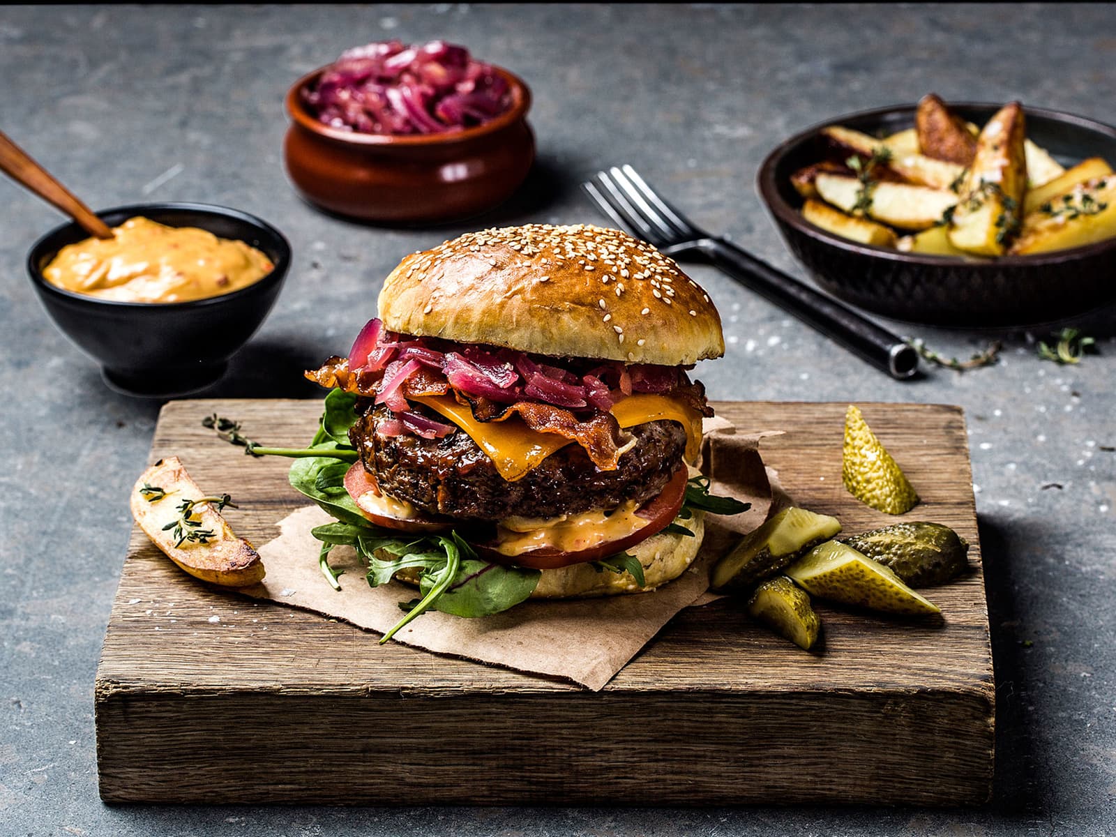 Hjemmelaget burger med bacon, cheddarost og rødløk