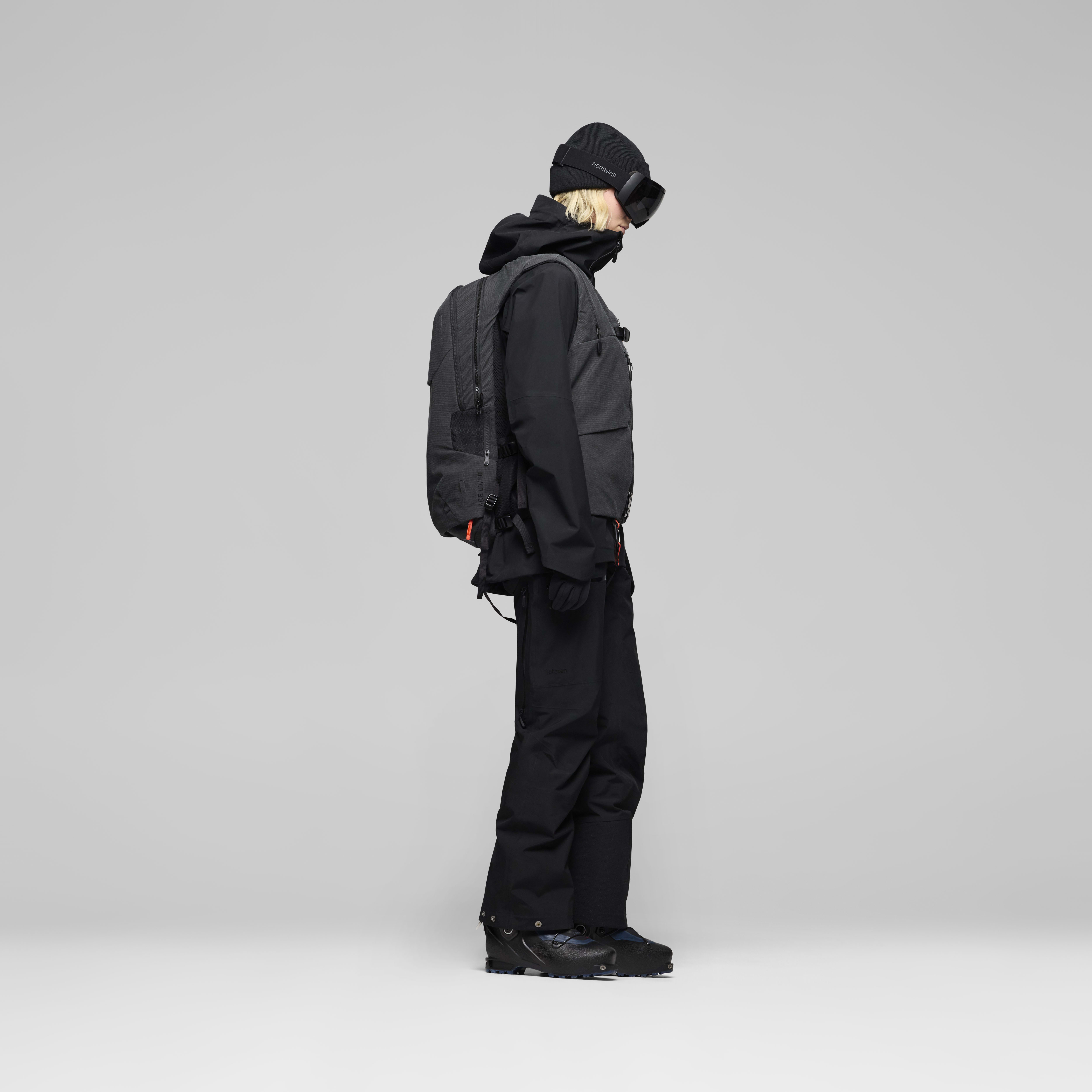 Female Look back image of lofoten Avi ACE 15L Pack Caviar Black