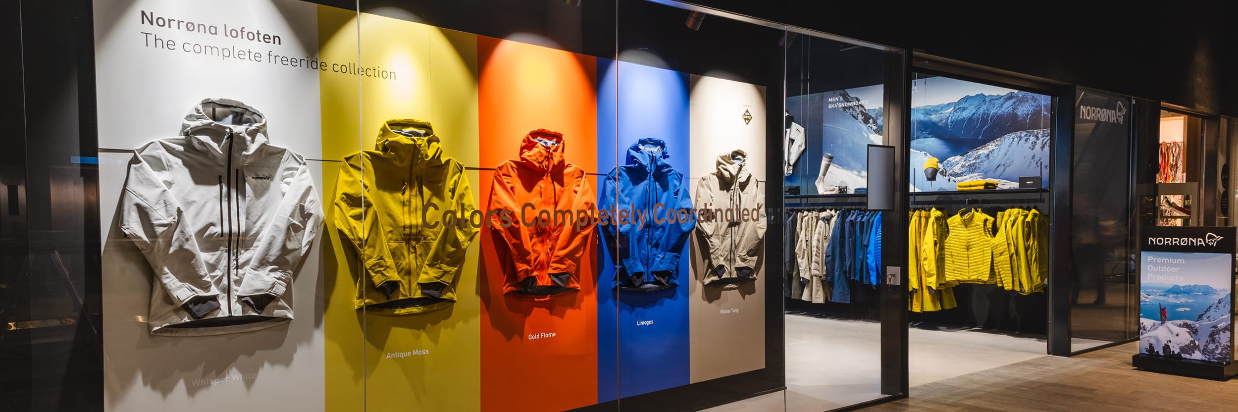 Norrøna store display with lofoten freeride jackets in white, yellow, orange, blue, and beige on a color-blocked wall.