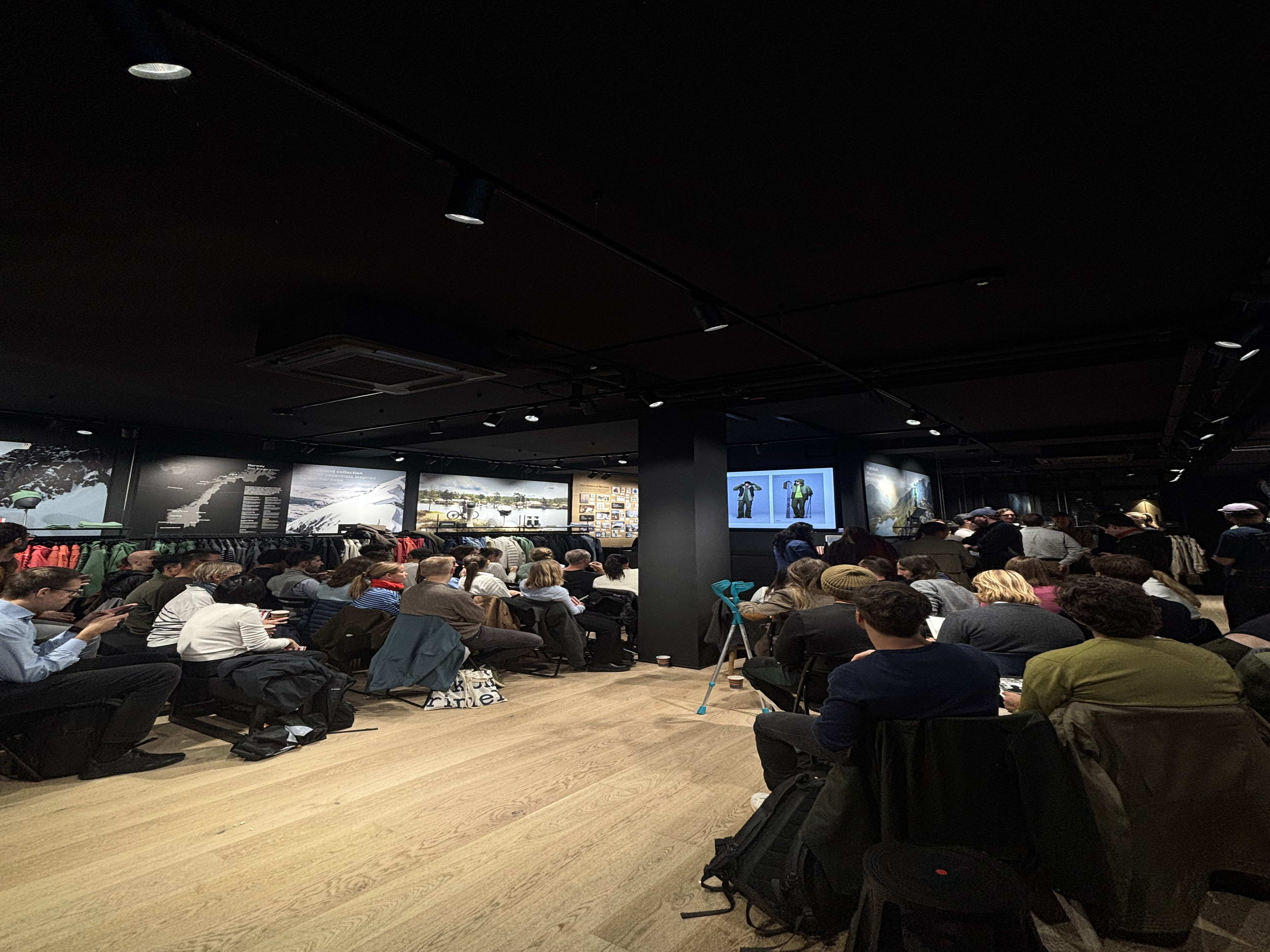 People wearing Norrøna clothing seated for a store presentation.