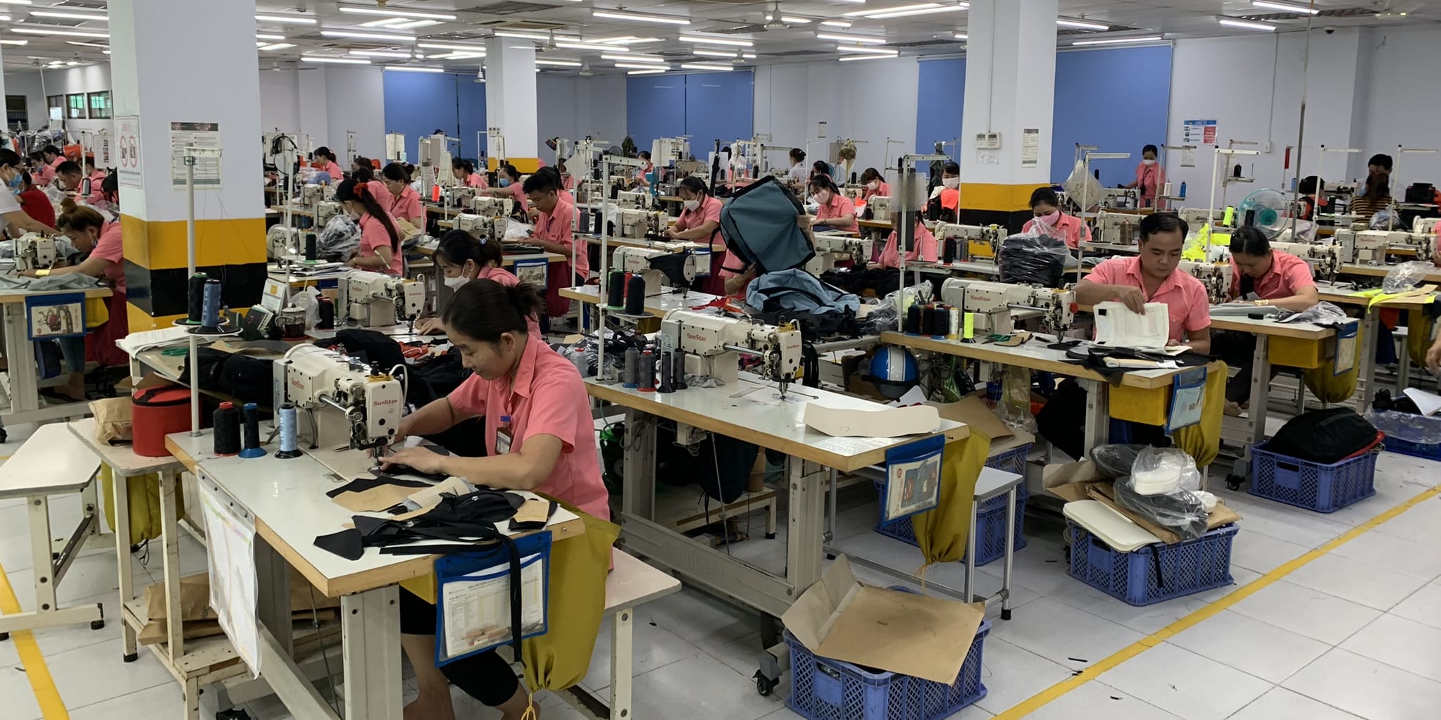 A factory floor with several people sewing Norrøna products. 
