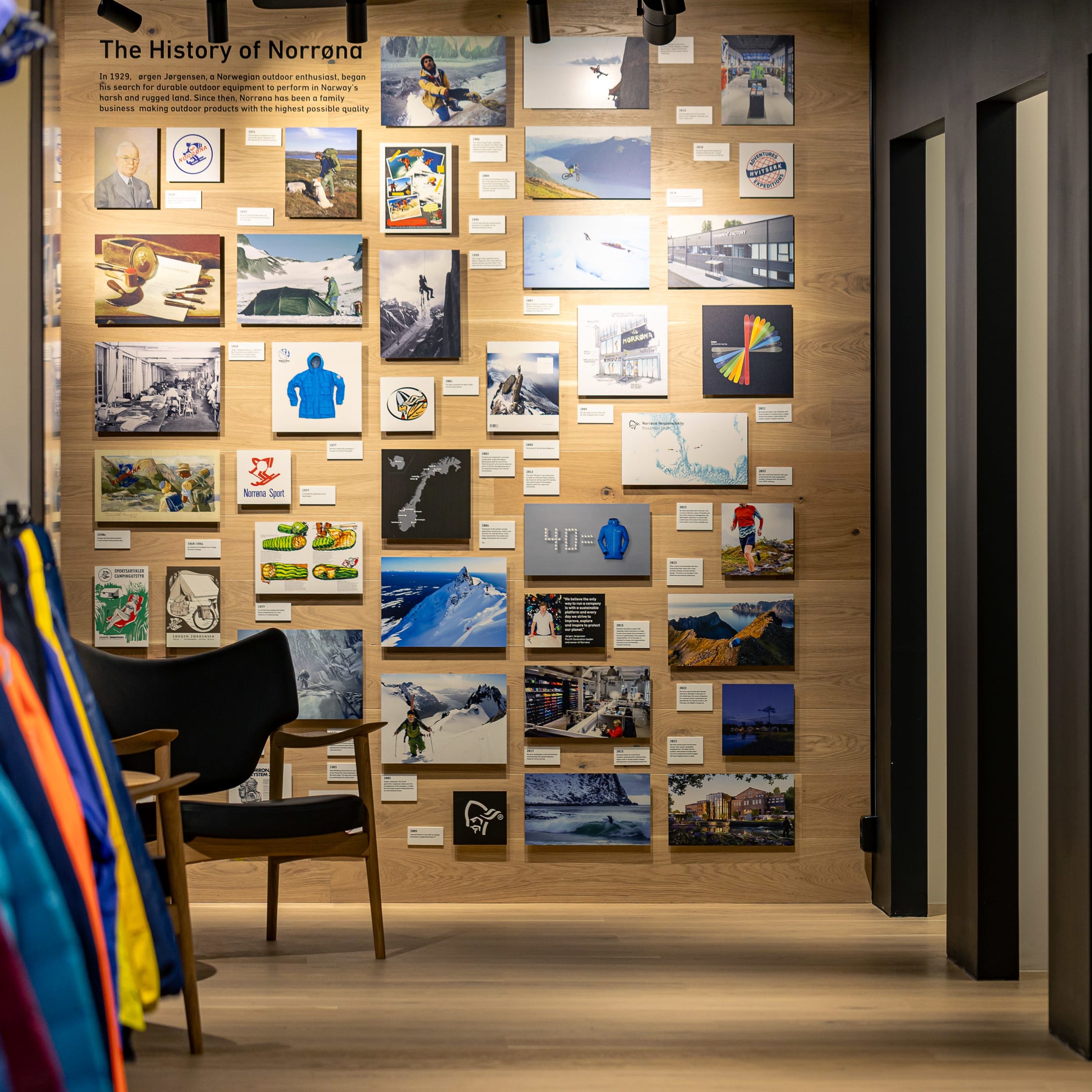 Retail display featuring a "The History of Norrøna" photo wall, a chair, and colorful Norrøna products.