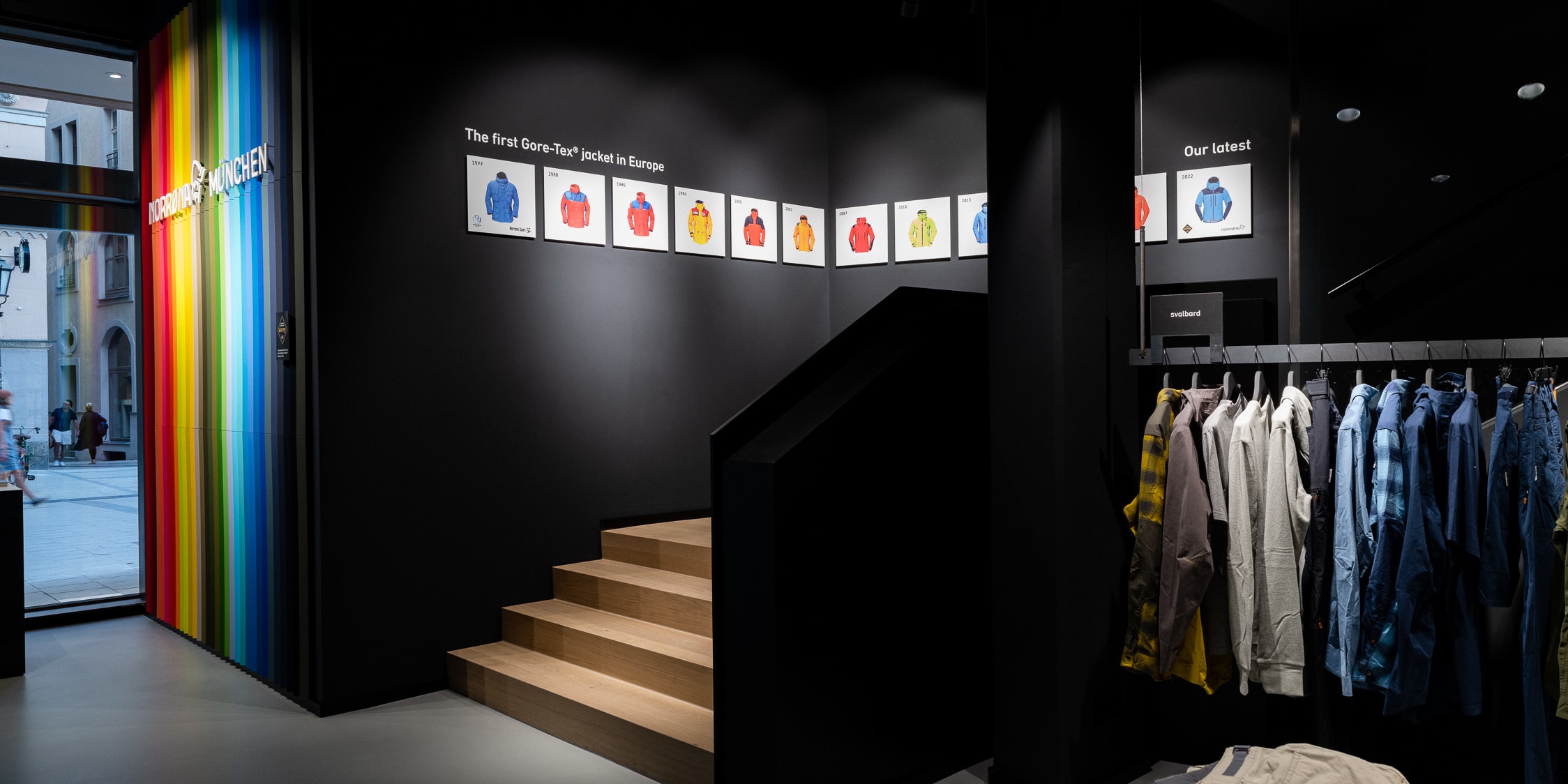 A Norrøna store in Munich. A wall showcases the history of Norrøna's Gore-Tex jackets and their latest jackets.  A staircase leads up to the second floor.