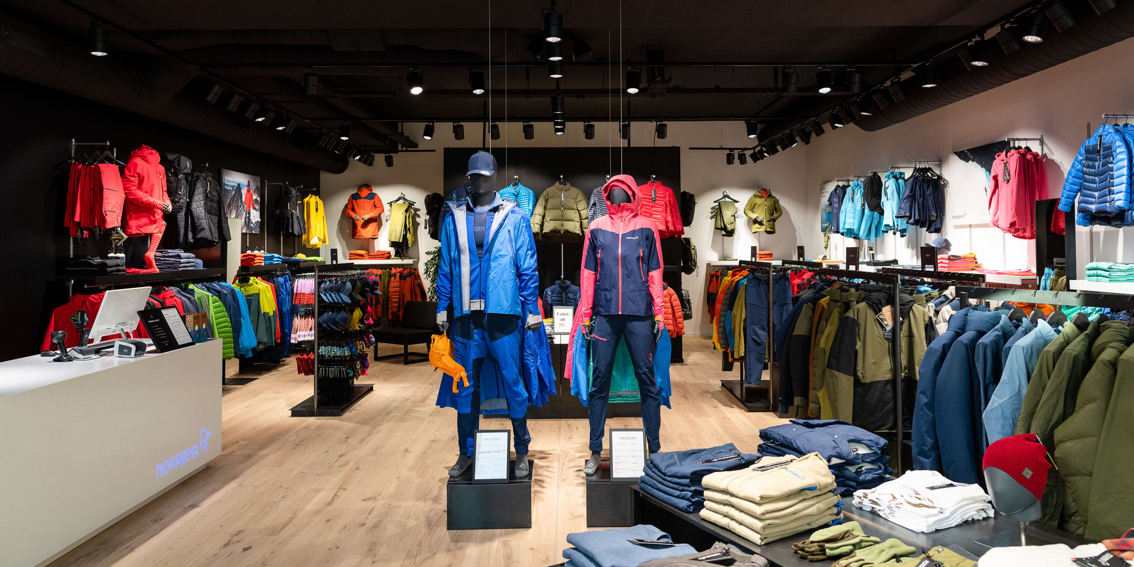 Inside a Norrøna retail store with colorful outdoor clothing displayed on racks and mannequins.