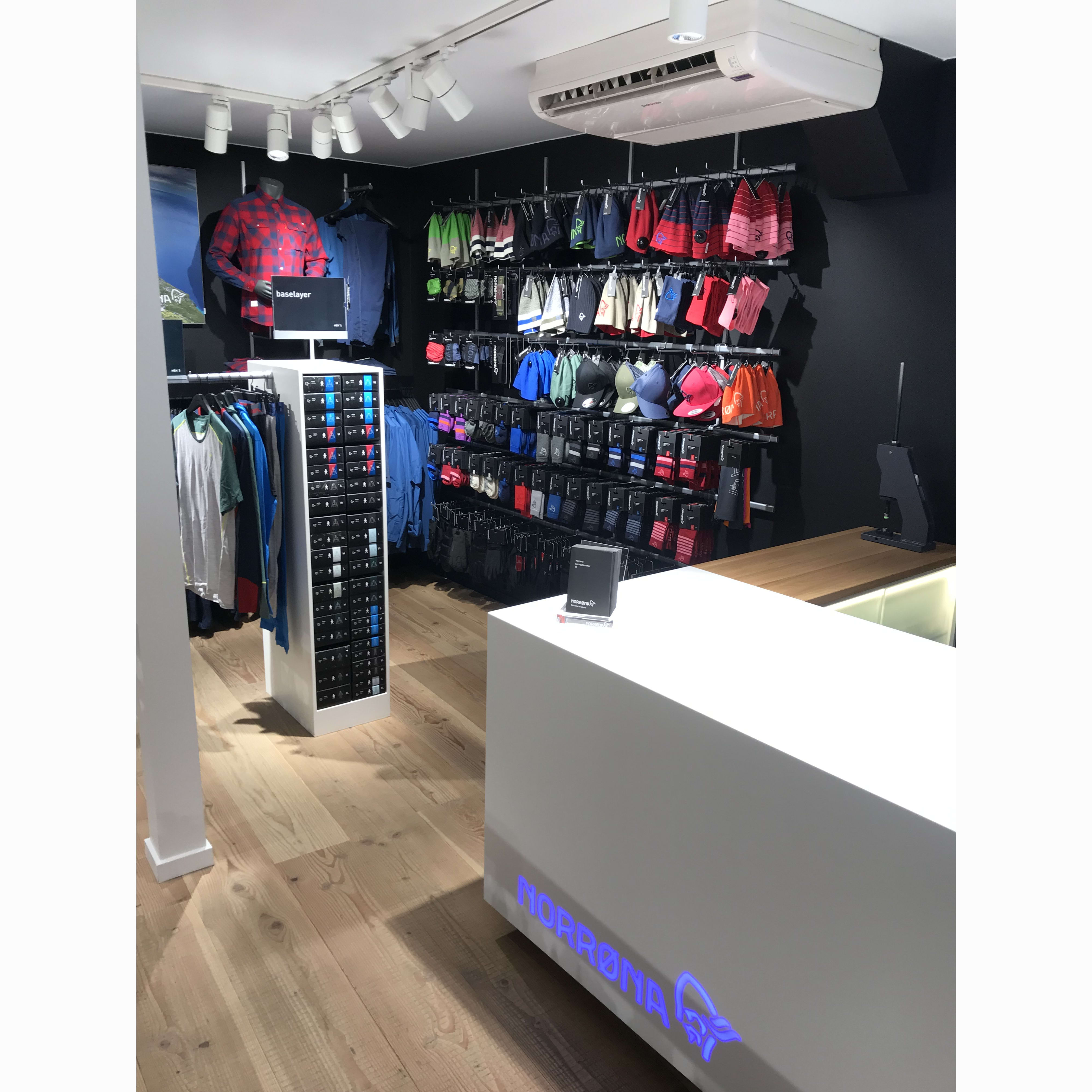 Norrøna store display featuring colorful clothing, hats, accessories, and a branded counter.