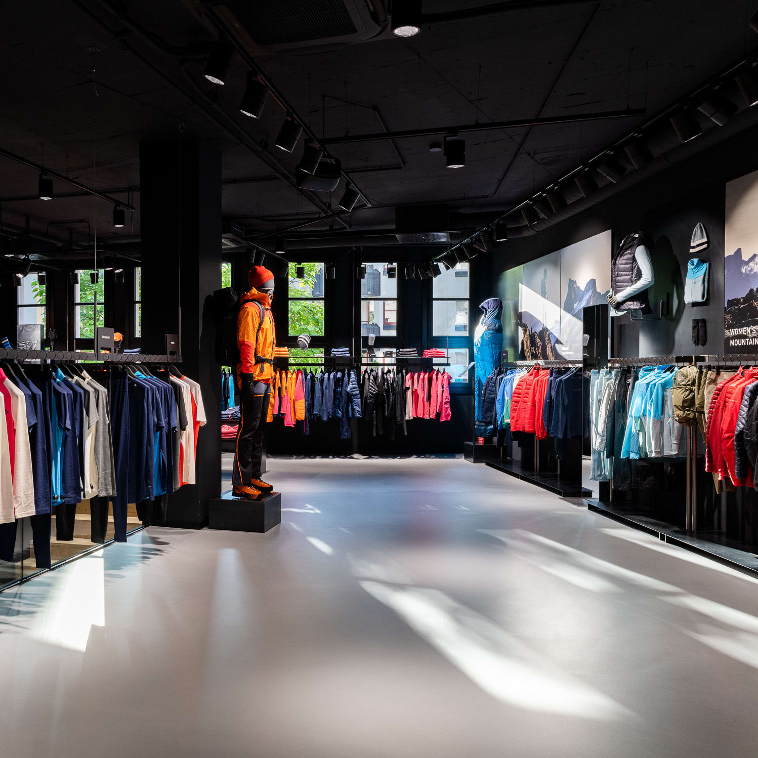 A well lit Norrøna store with mannequins displaying outerwear and racks of clothing.  
