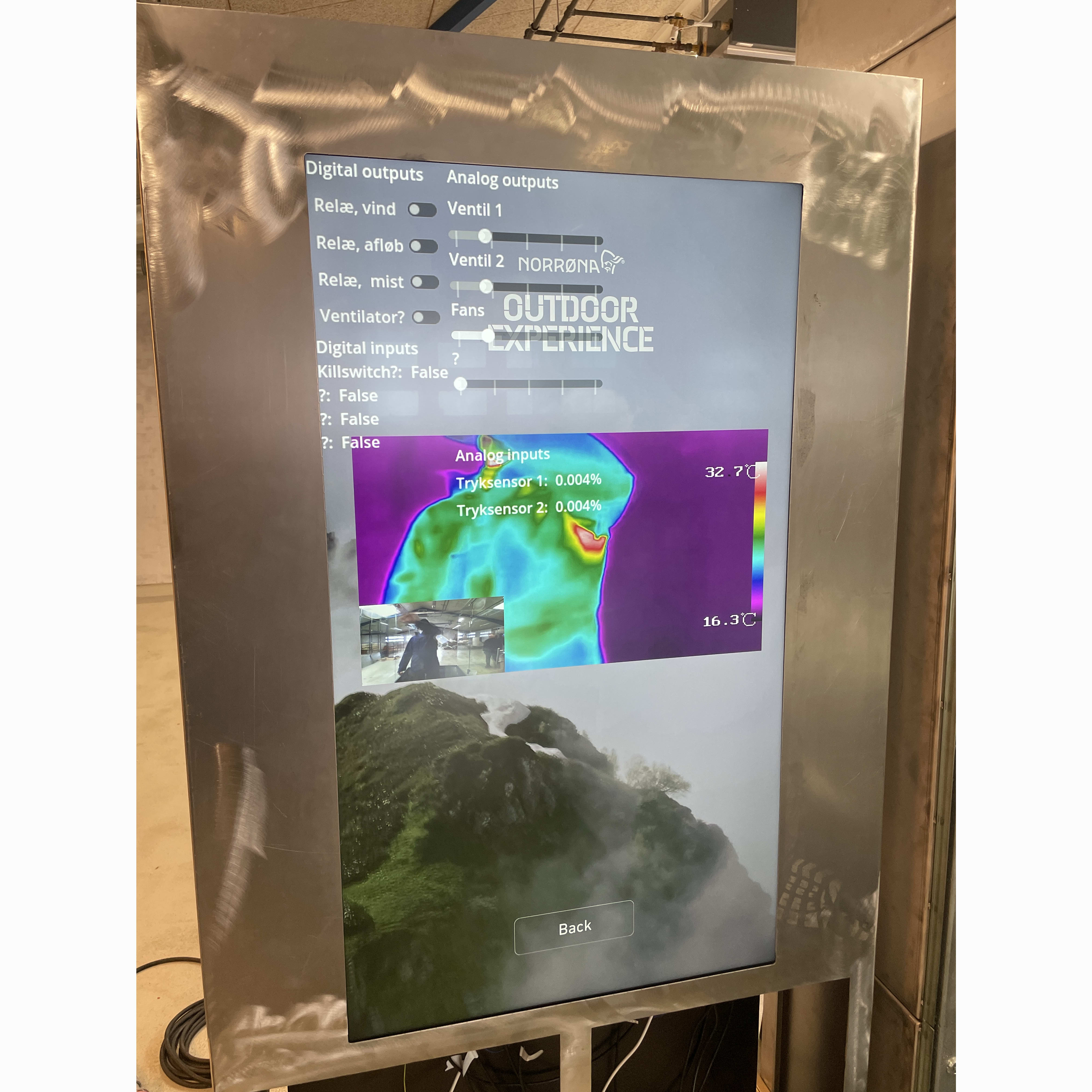 A screen displaying Norrøna branding, "Outdoor Experience", a thermal image of a mountain, and data readings. A smaller image shows a person wearing a jacket.