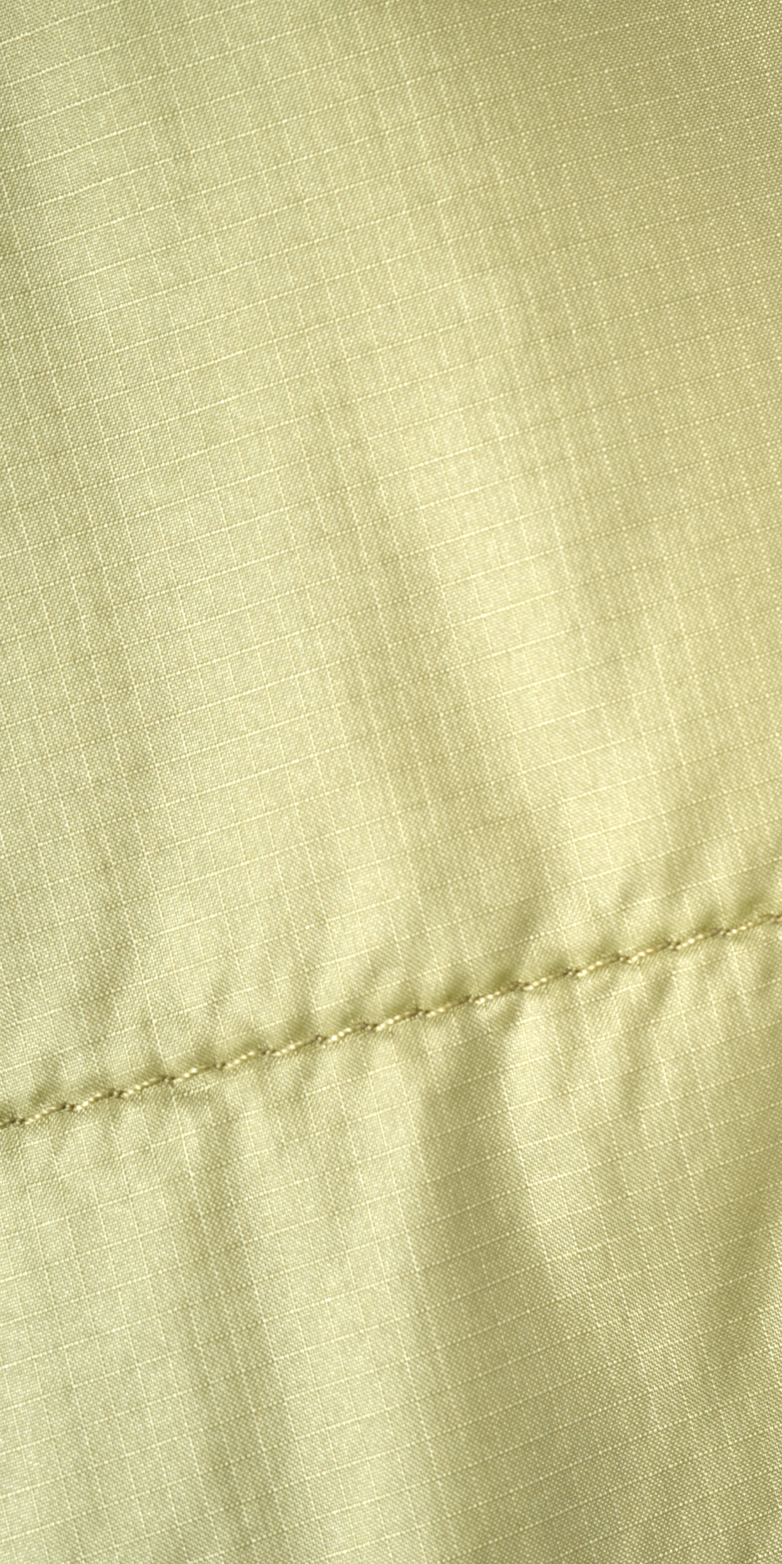 Closeup of a Norrøna jacket's light green fabric with a zipper. 
