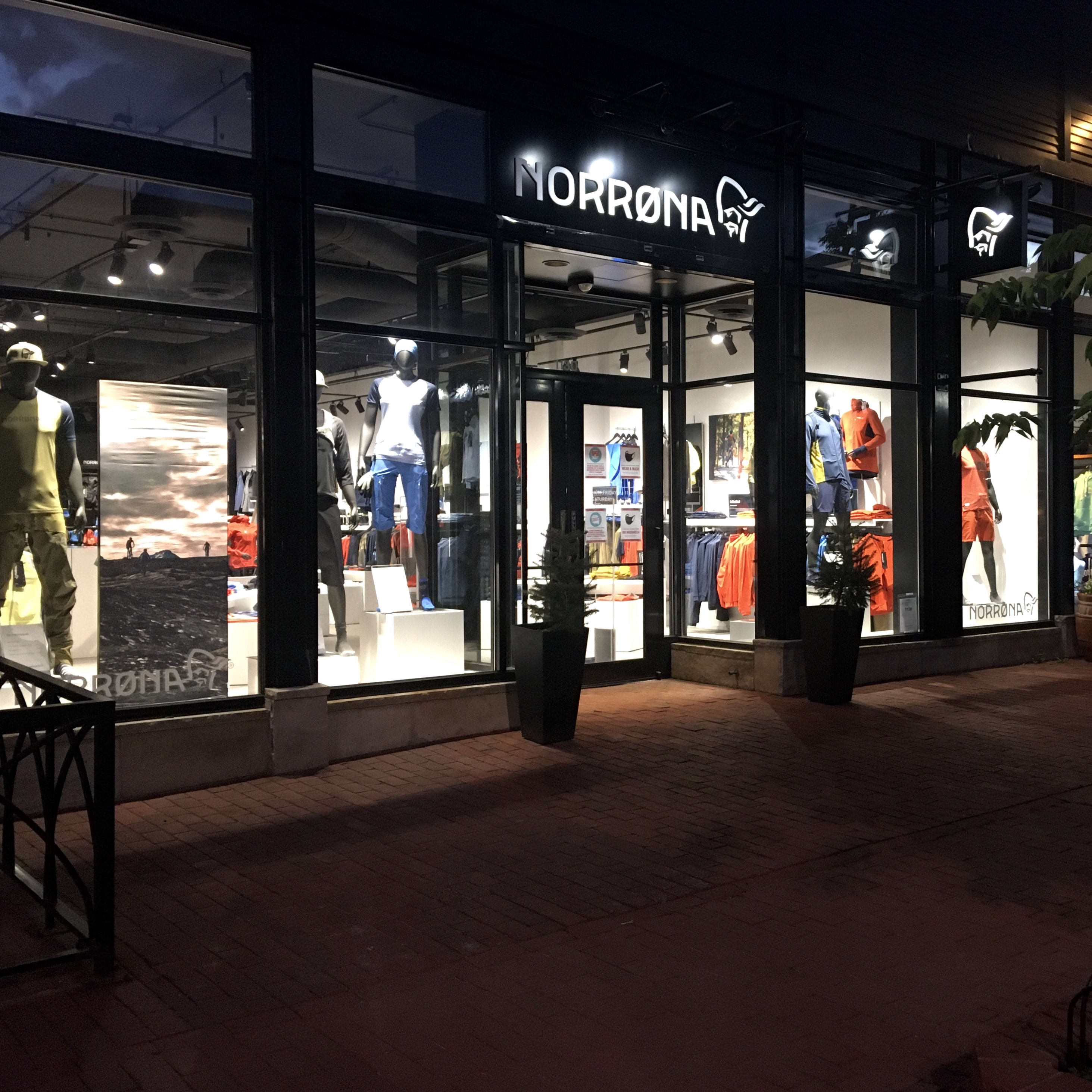 Nighttime view of a Norrøna store with mannequins wearing clothing.  The storefront is lit up with signage.