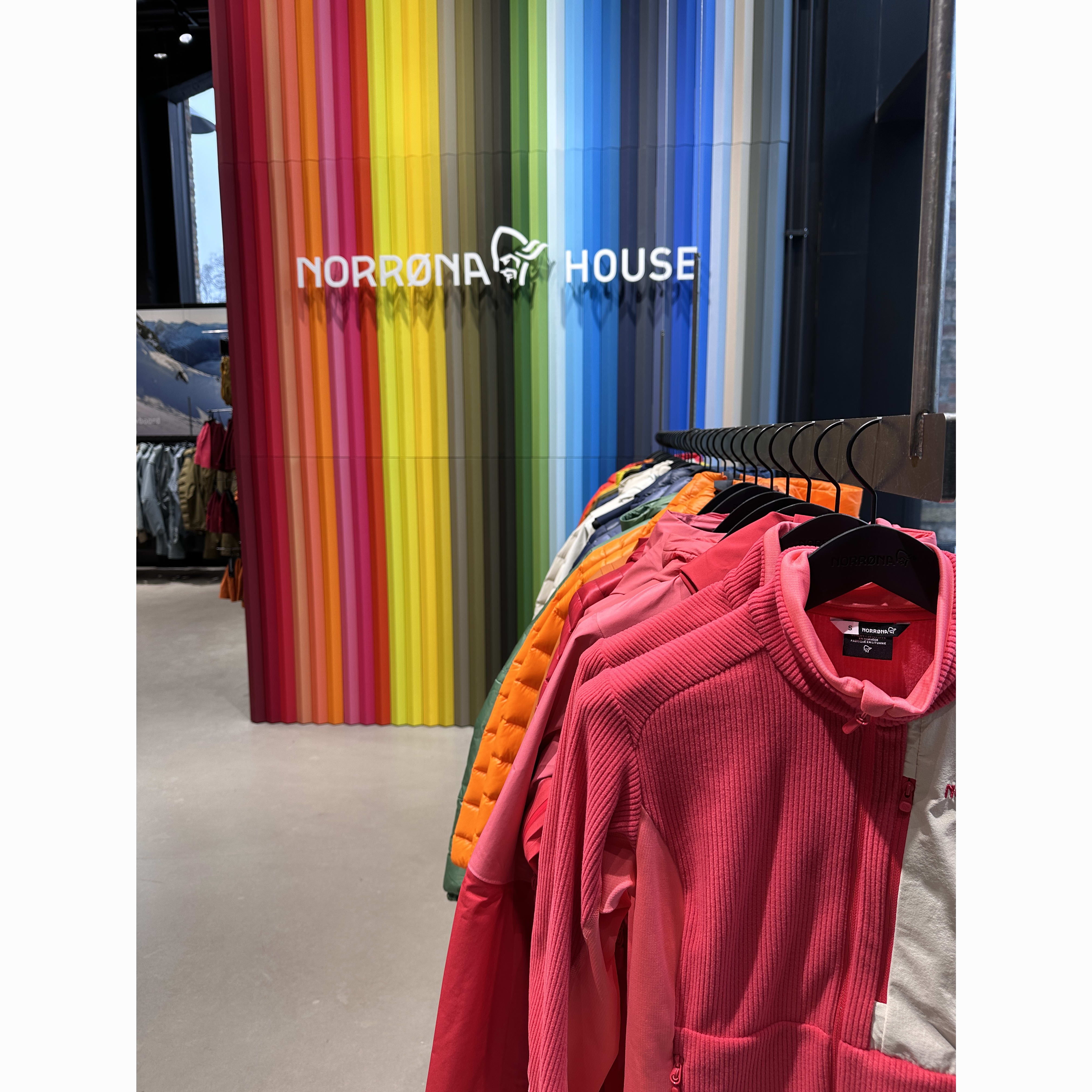 Close-up of a rack of Norrøna clothing in varying colors against a striped background with the brand name.