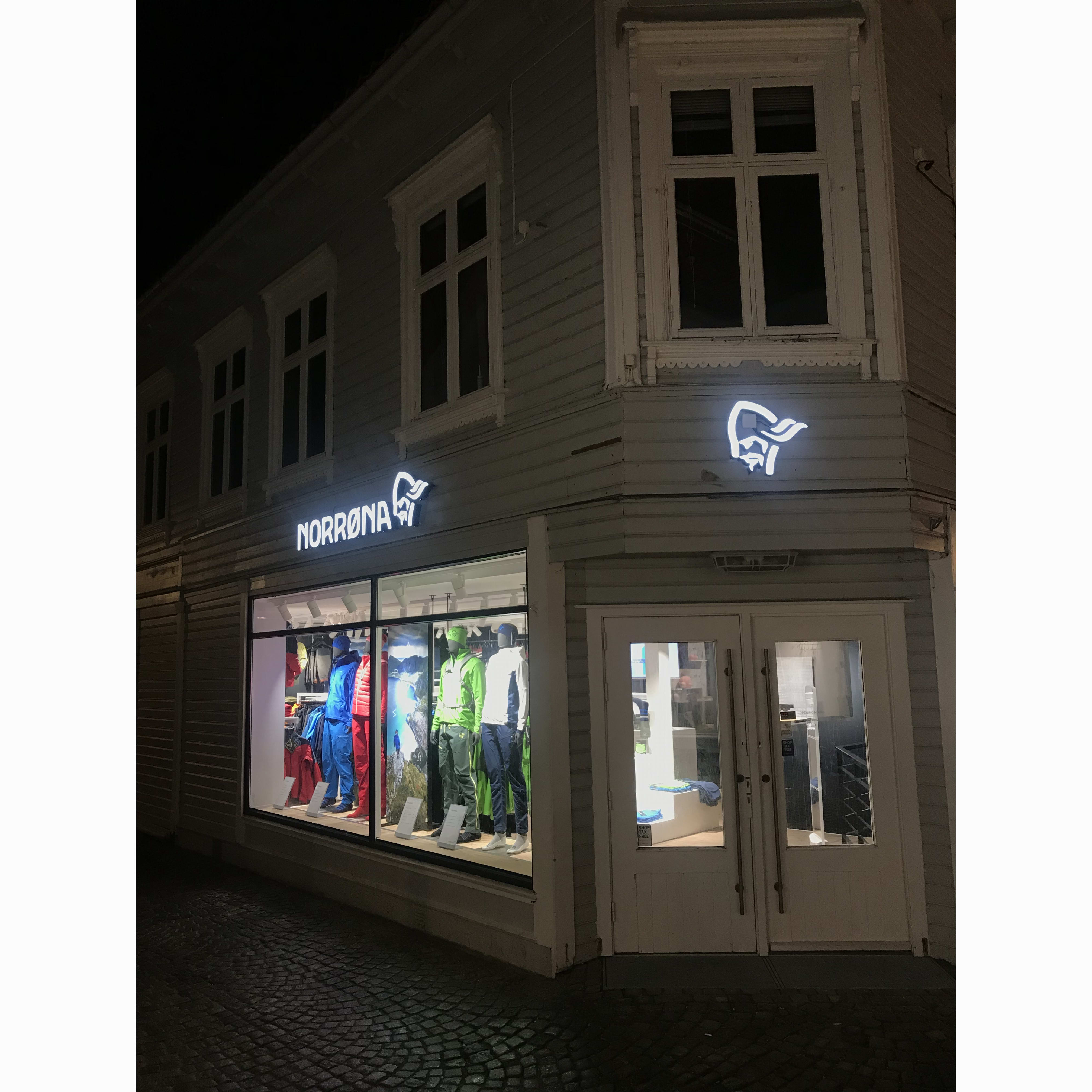 Norrøna store facade at night with colorful Norrøna clothing displayed in the window.