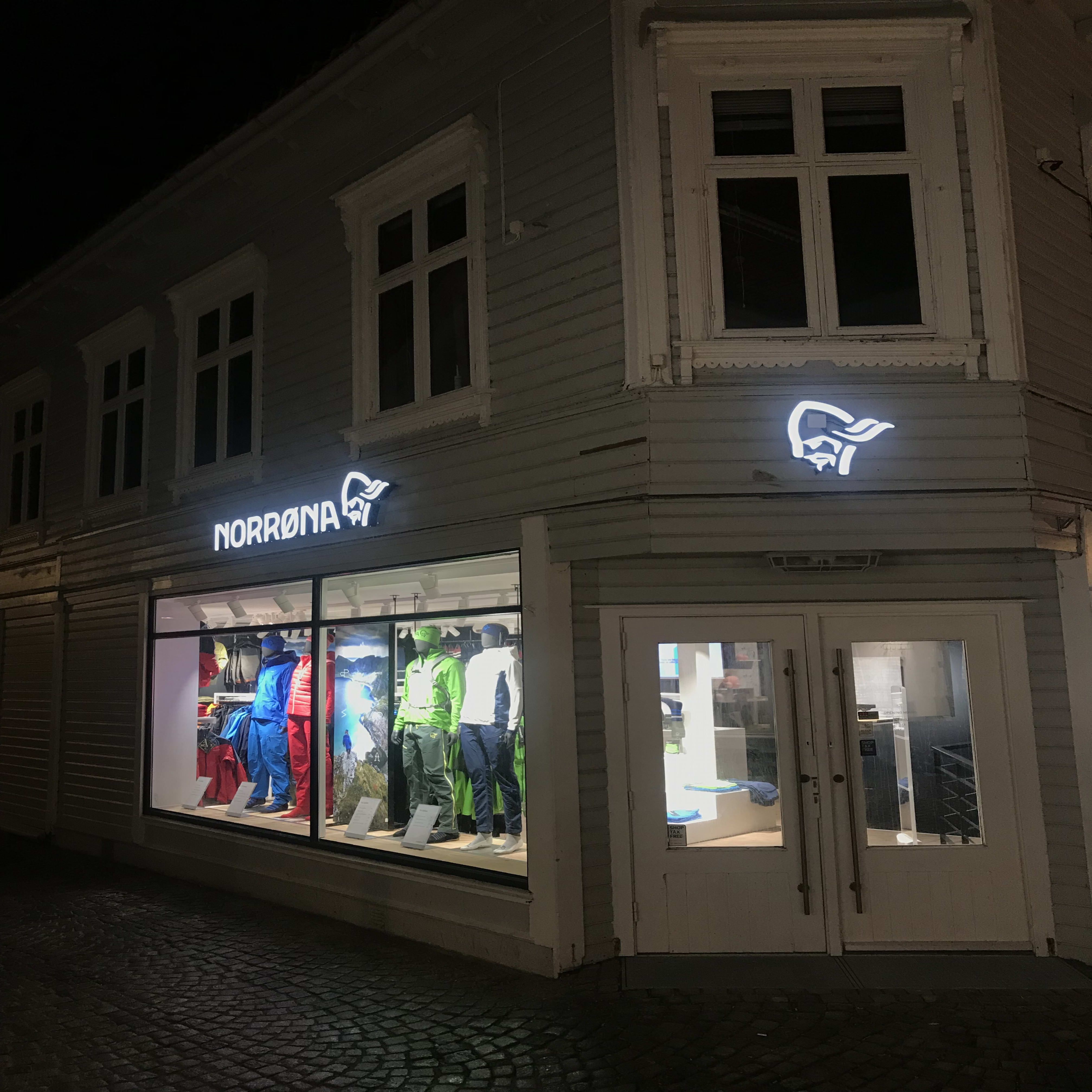 Norrøna store facade at night with colorful Norrøna clothing displayed in the window.