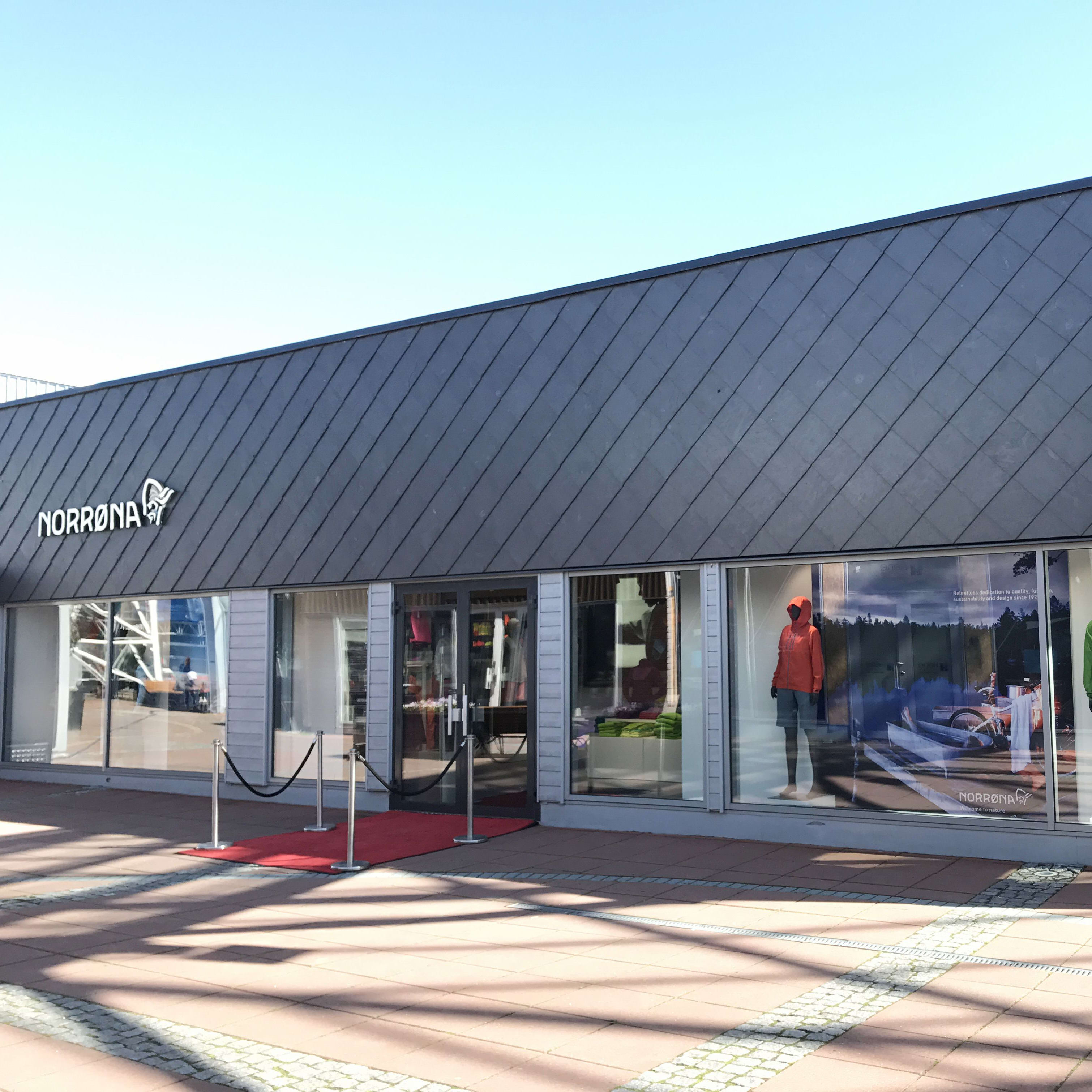A Norrøna store storefront with a red carpet and mannequins wearing Norrøna outerwear. 
