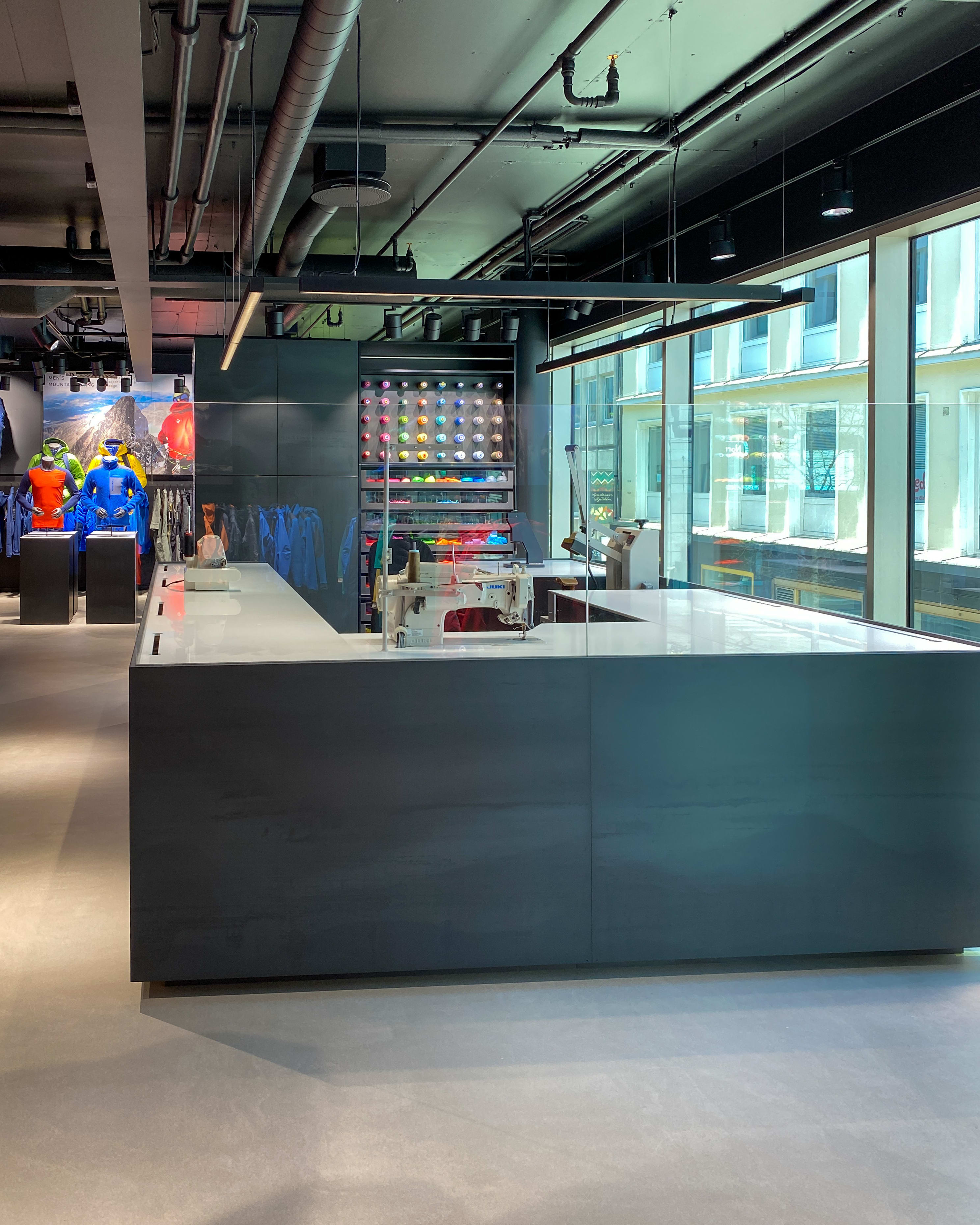 A modern retail space showcasing Norrøna clothing with a sewing machine and colorful thread on a table. 
