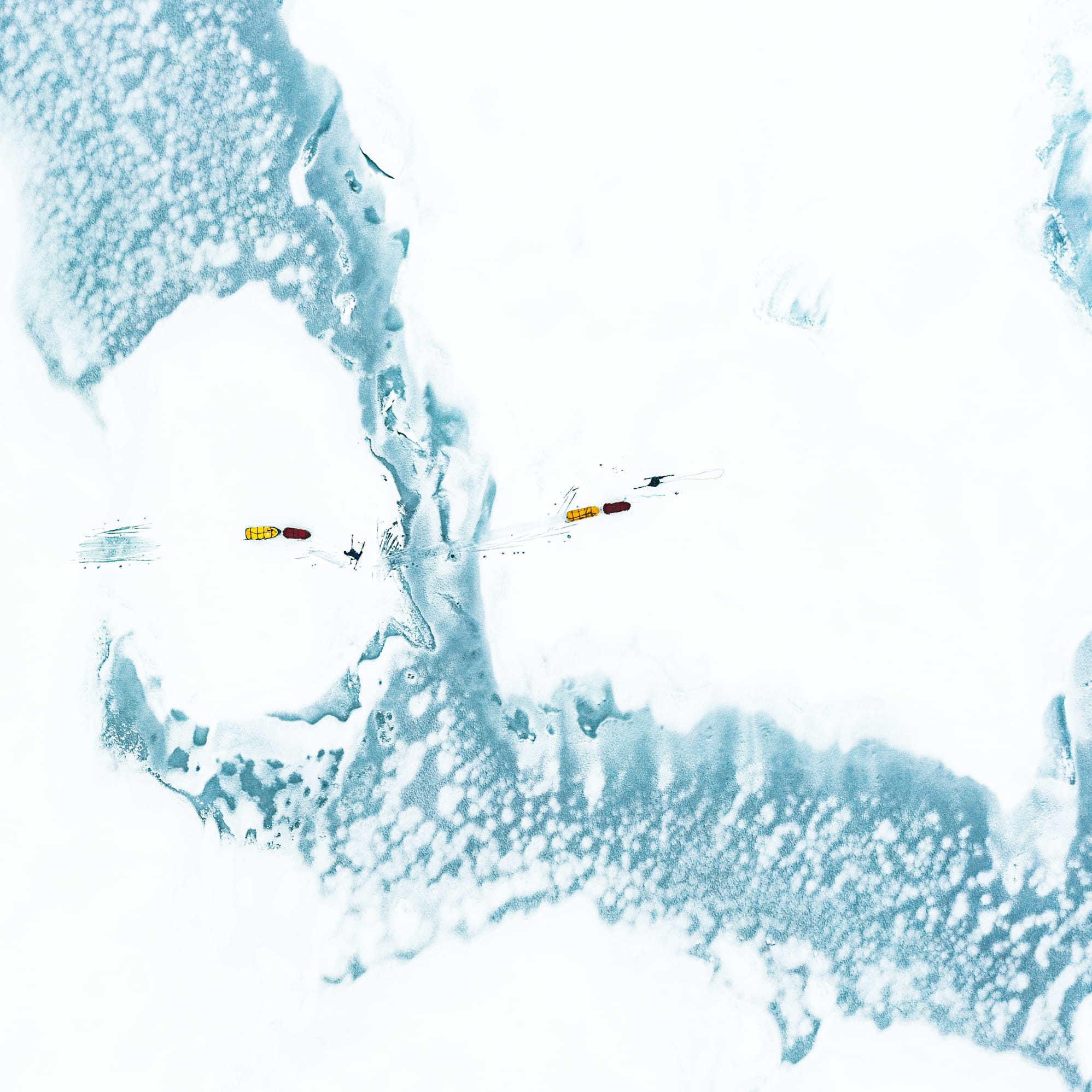 Aerial view of two yellow and red objects in a snow-covered landscape.