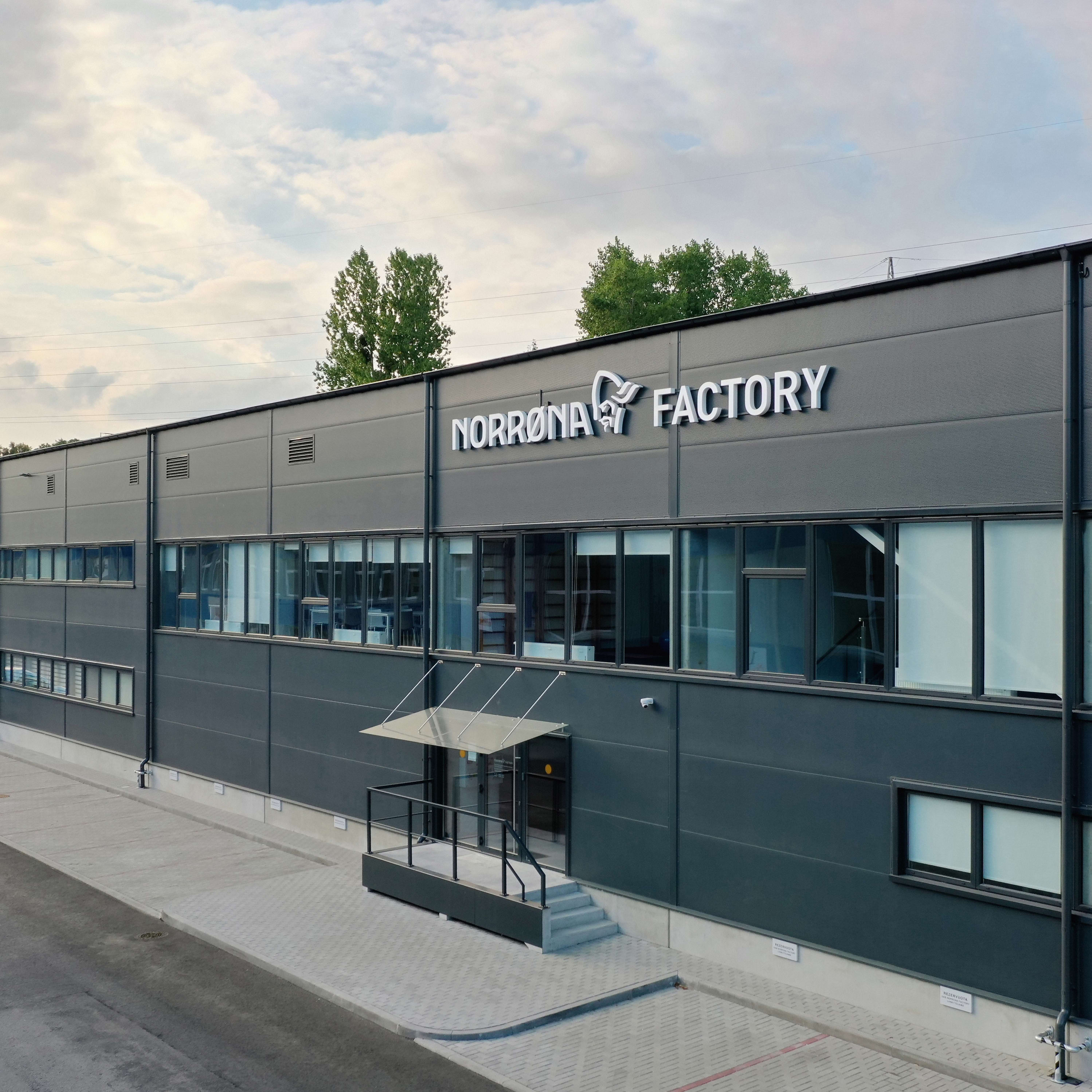 Norrøna Factory building with a gray exterior, multiple windows, and a paved entrance.
