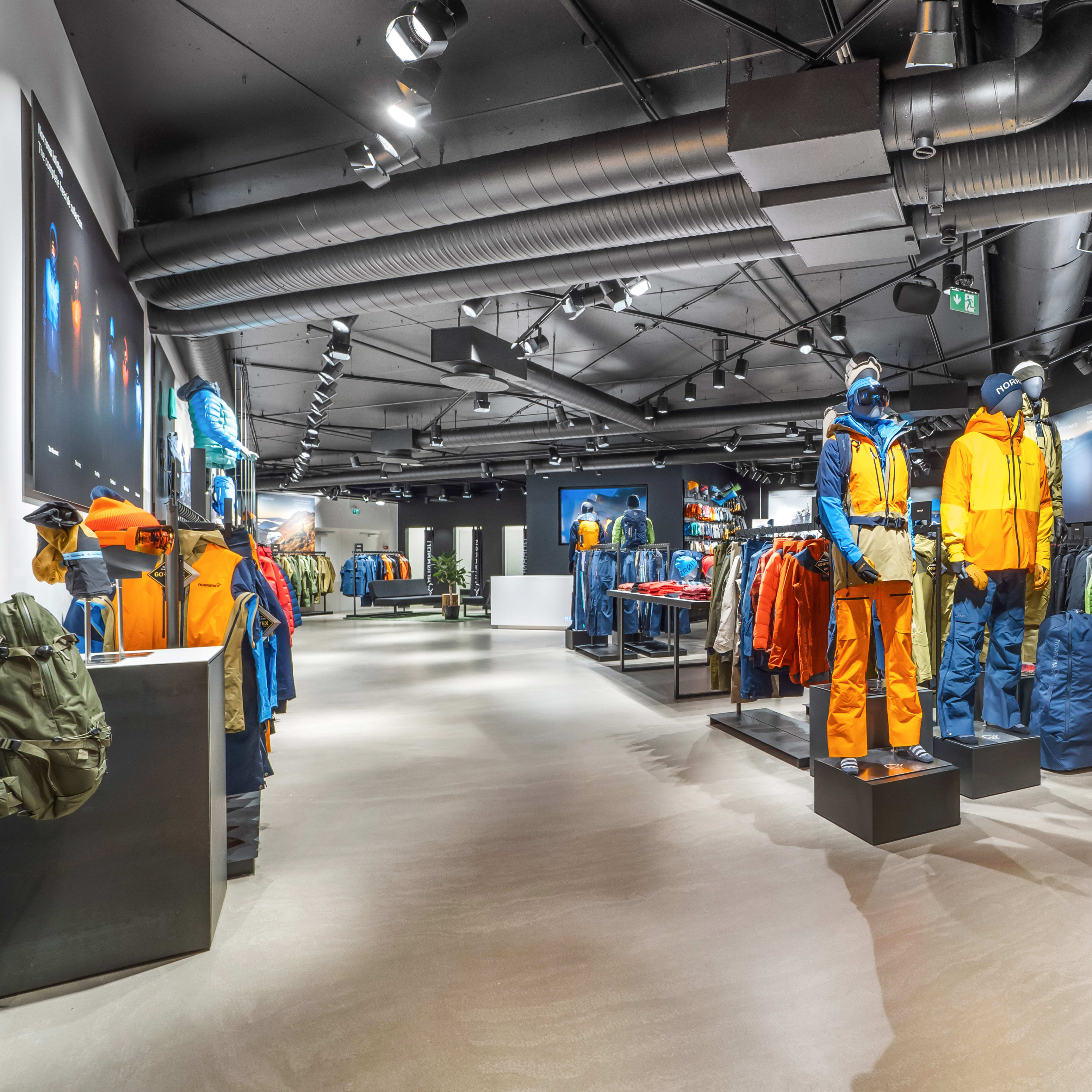 Interior of a modern retail store displaying colorful Norrøna outdoor clothing on mannequins and racks.