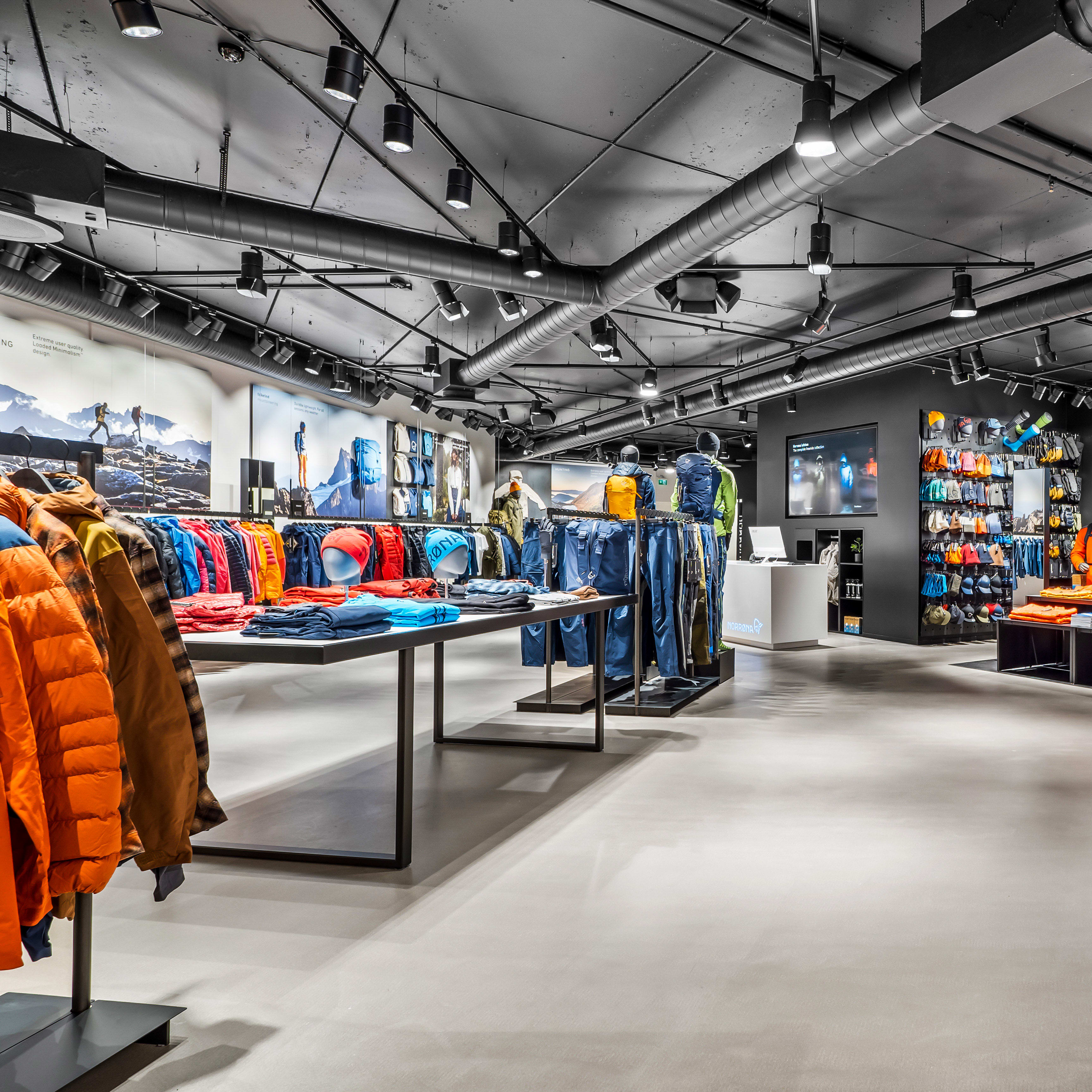 Interior of a modern retail store displaying colorful Norrøna products on clothing racks and tables.