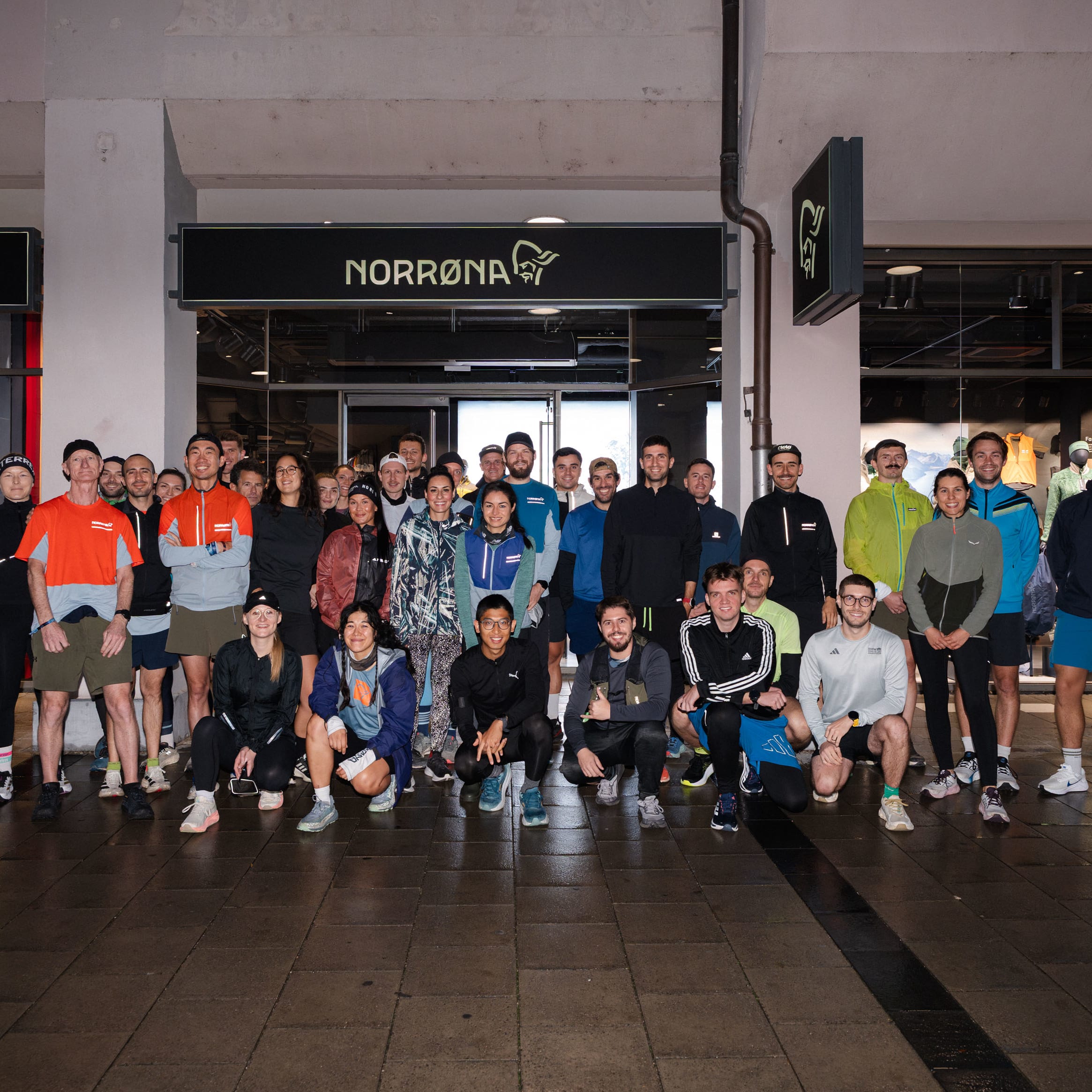 A group of people wearing Norrøna sportswear posing in front of a Norrøna store.