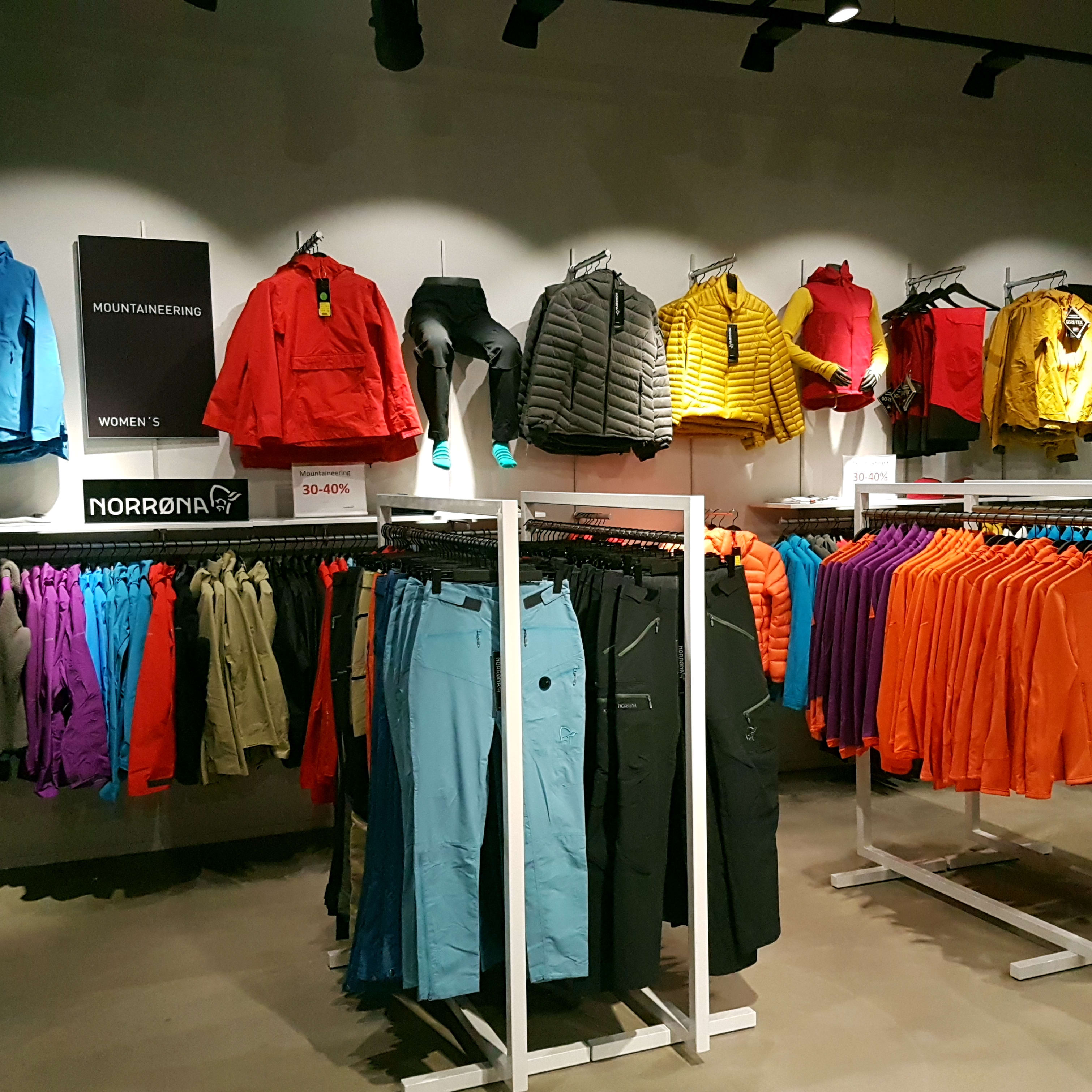 Colorful Norrøna women's mountaineering clothing displayed on racks in a retail store.