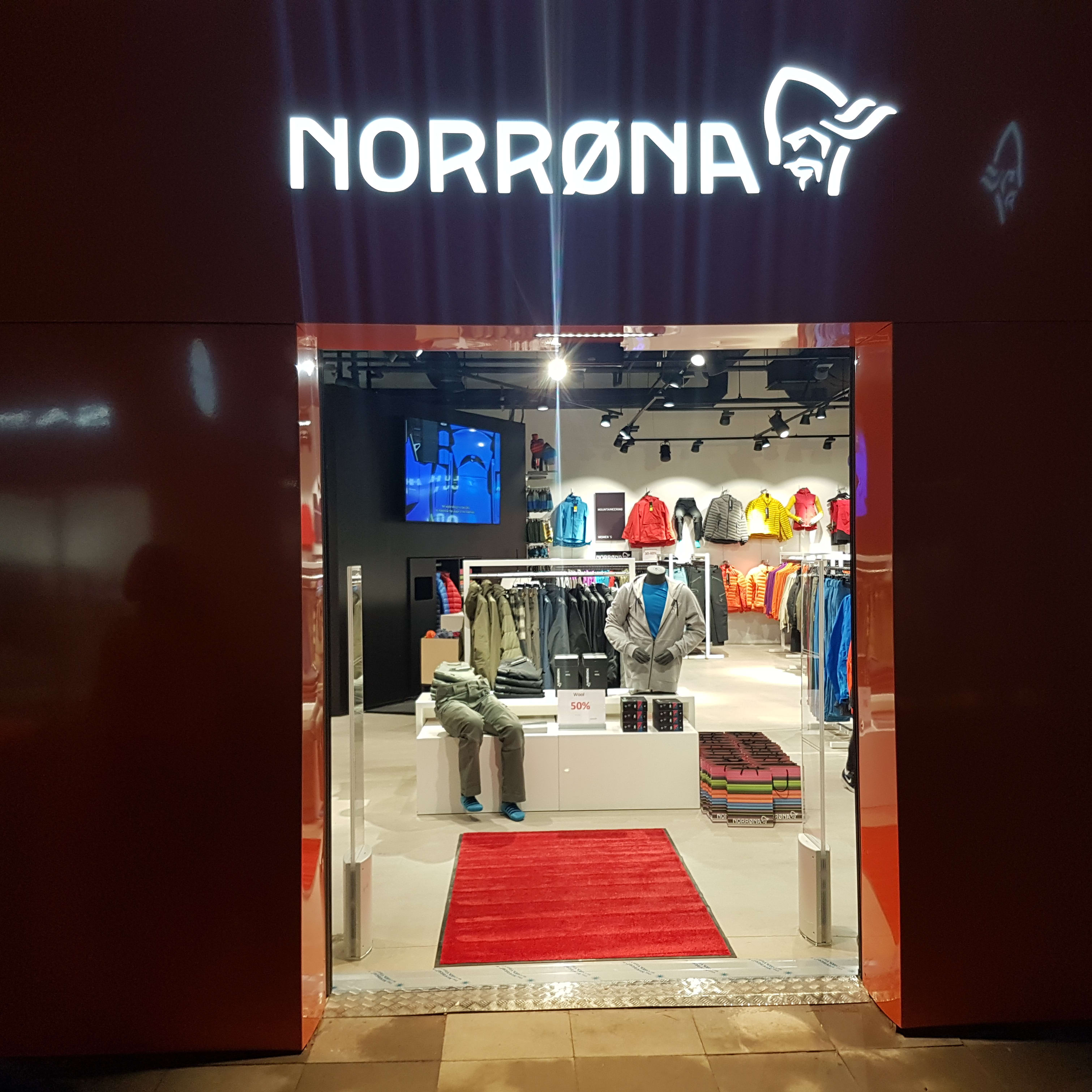 Norrøna storefront with a red entrance, bright logo, and Norrøna products on display inside.
