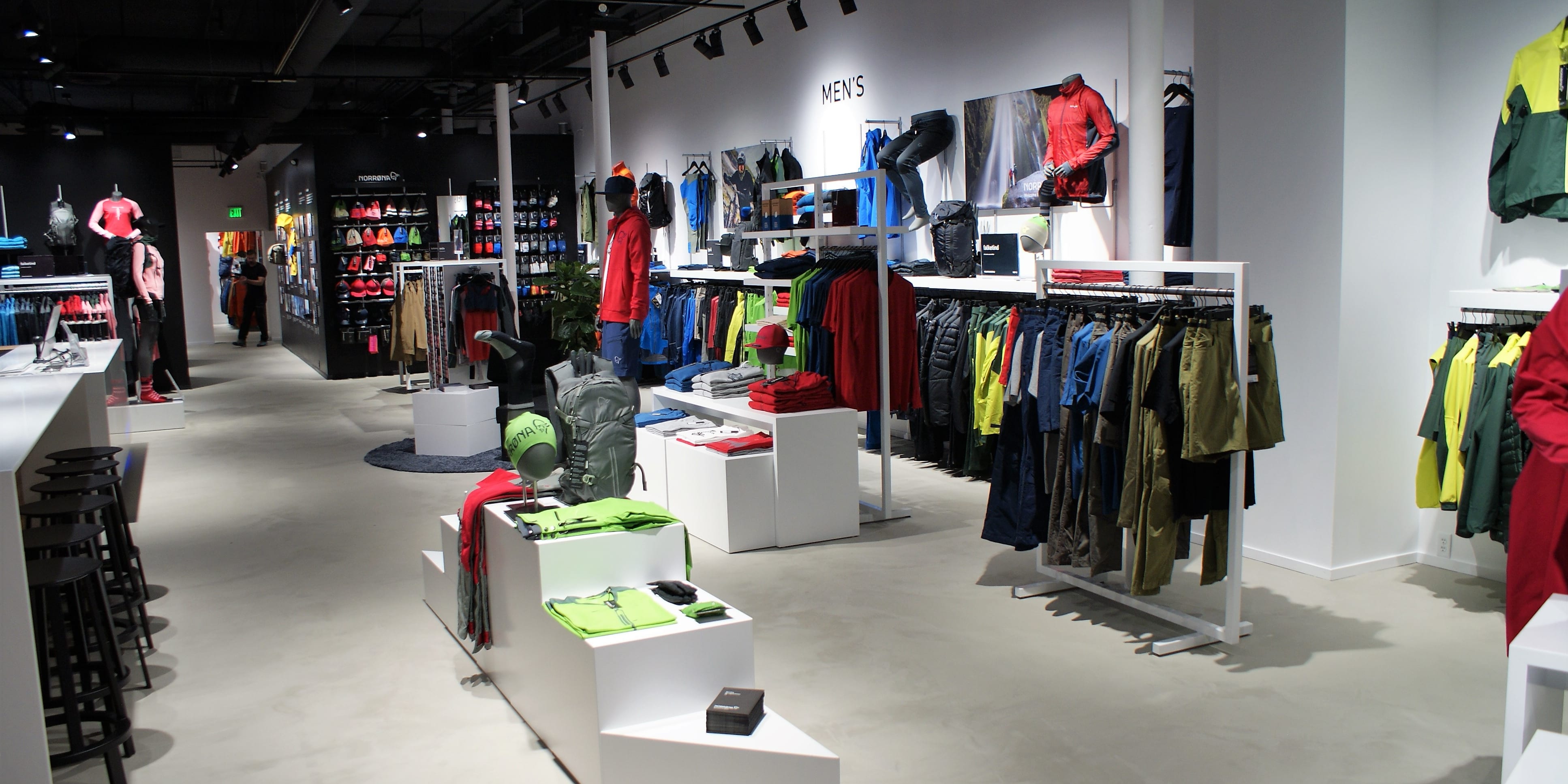 A well-lit Norrøna clothing store with mannequins, racks of clothing, and a backpack display. 
