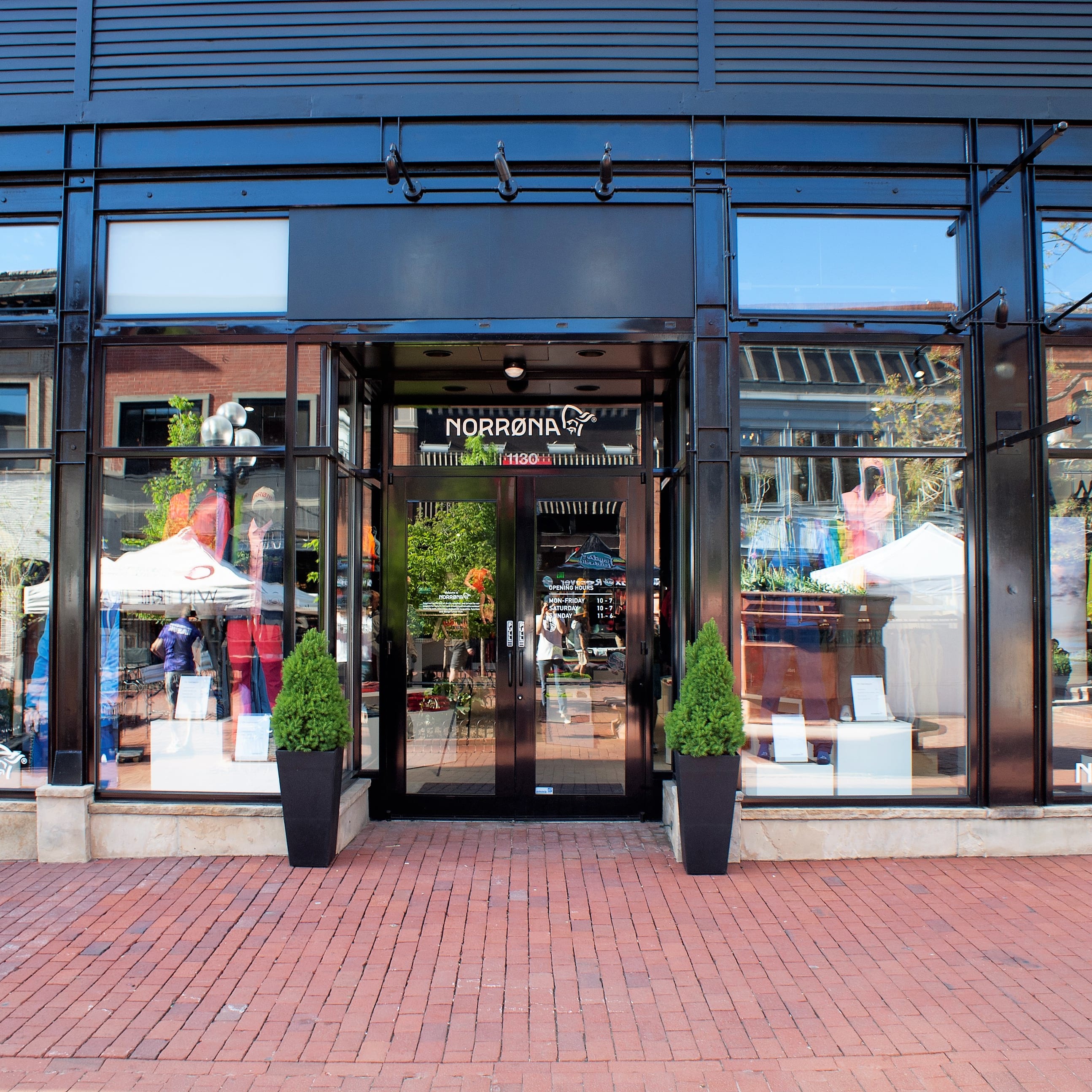 A storefront with a glass door that says "Norrøna" with the Norrøna logo. The windows are reflecting the street and building behind it. 
