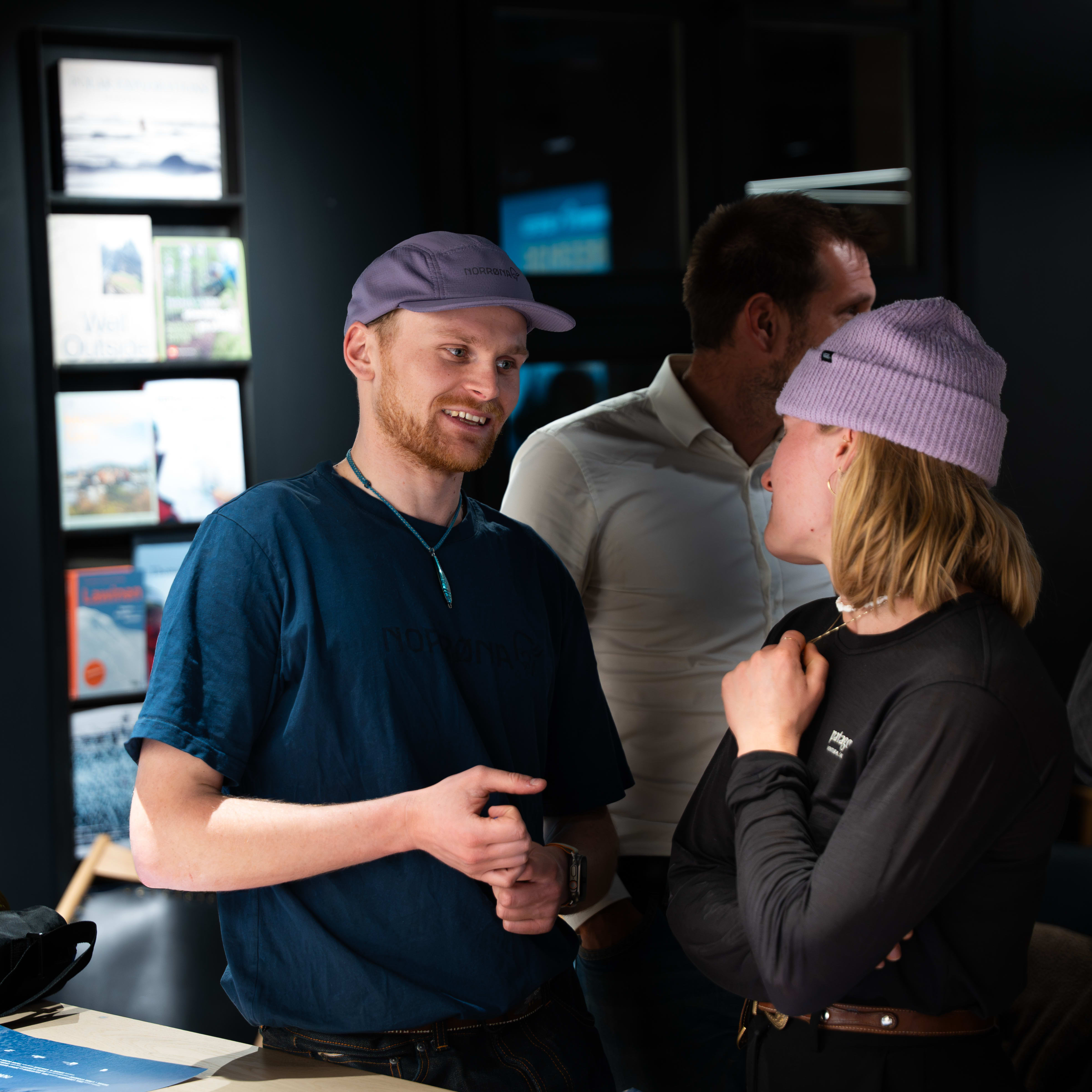 Two people wearing Norrøna clothing chatting over a table with posters.