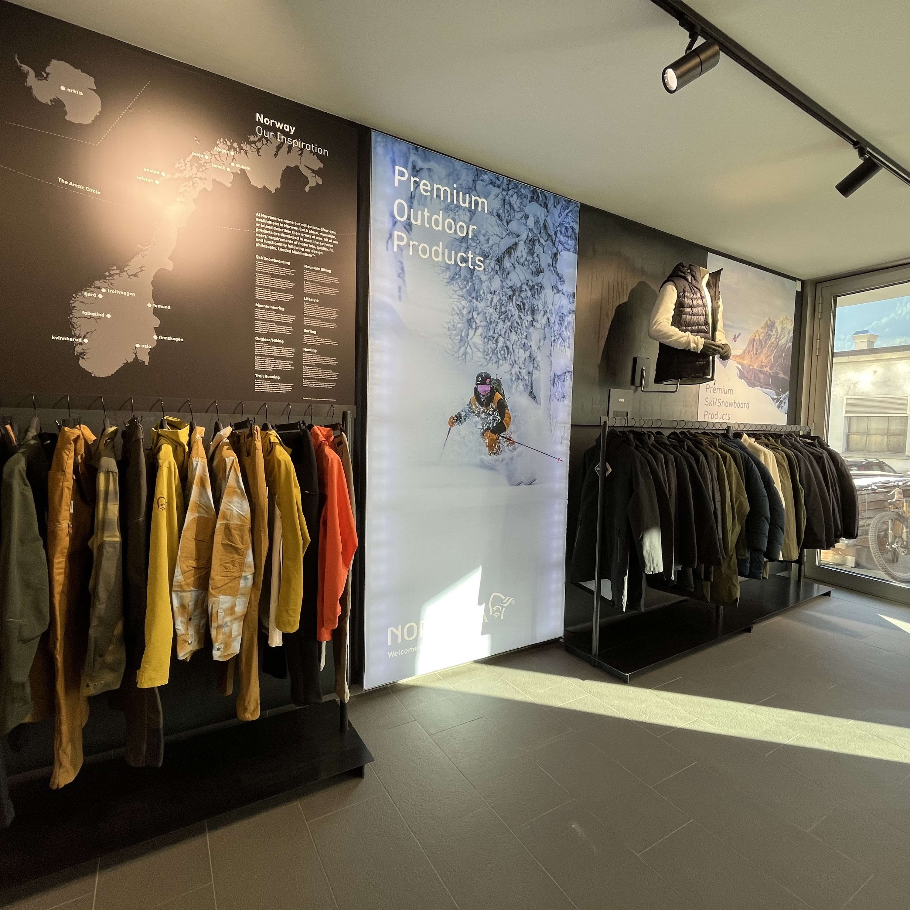 A Norrøna store interior with a rack of ski/snowboard jackets, mannequins, and a map of Norway. 
