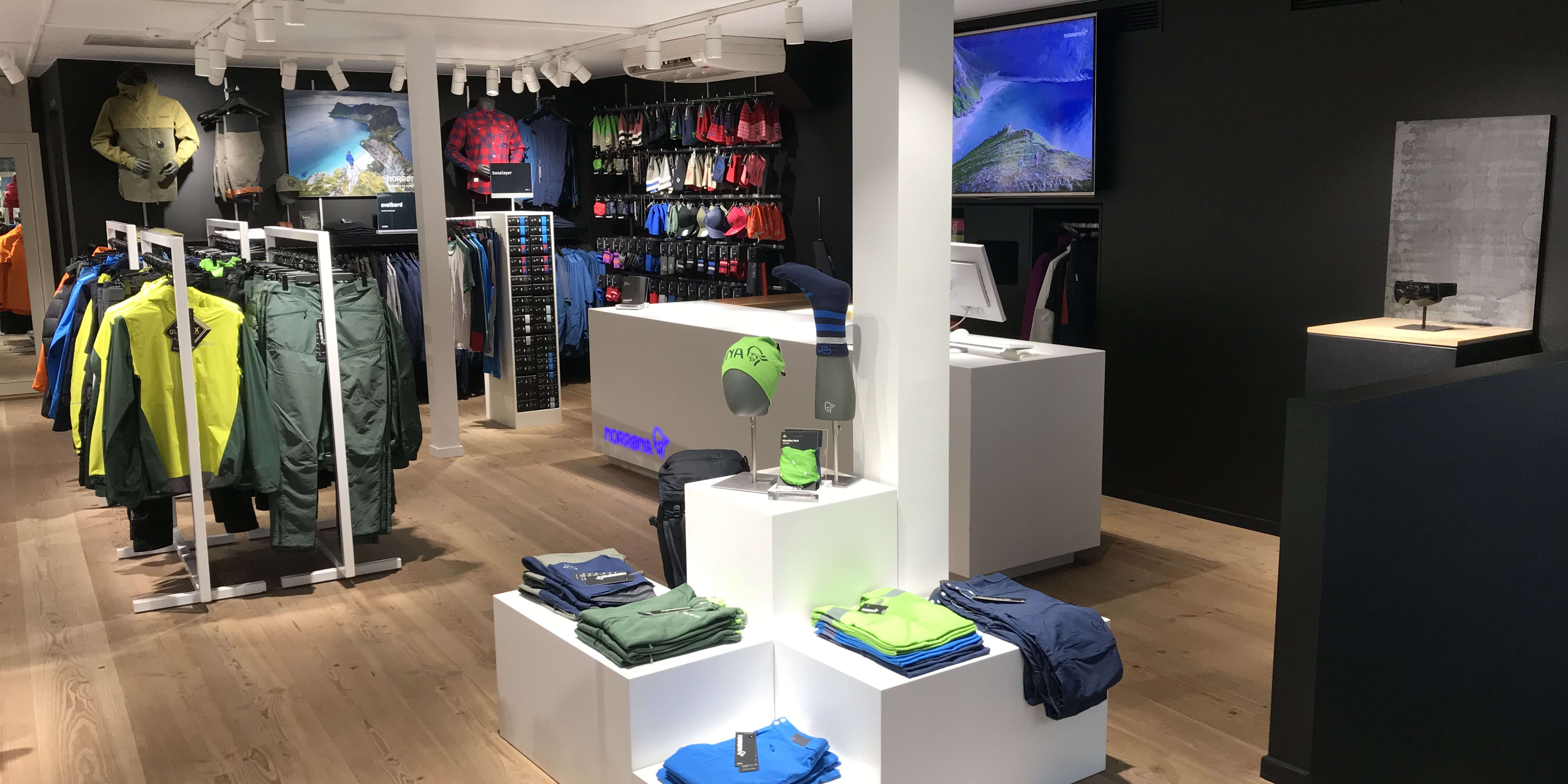 Interior of a Norrøna store displaying colorful outdoor apparel on clothing racks and modern white displays.