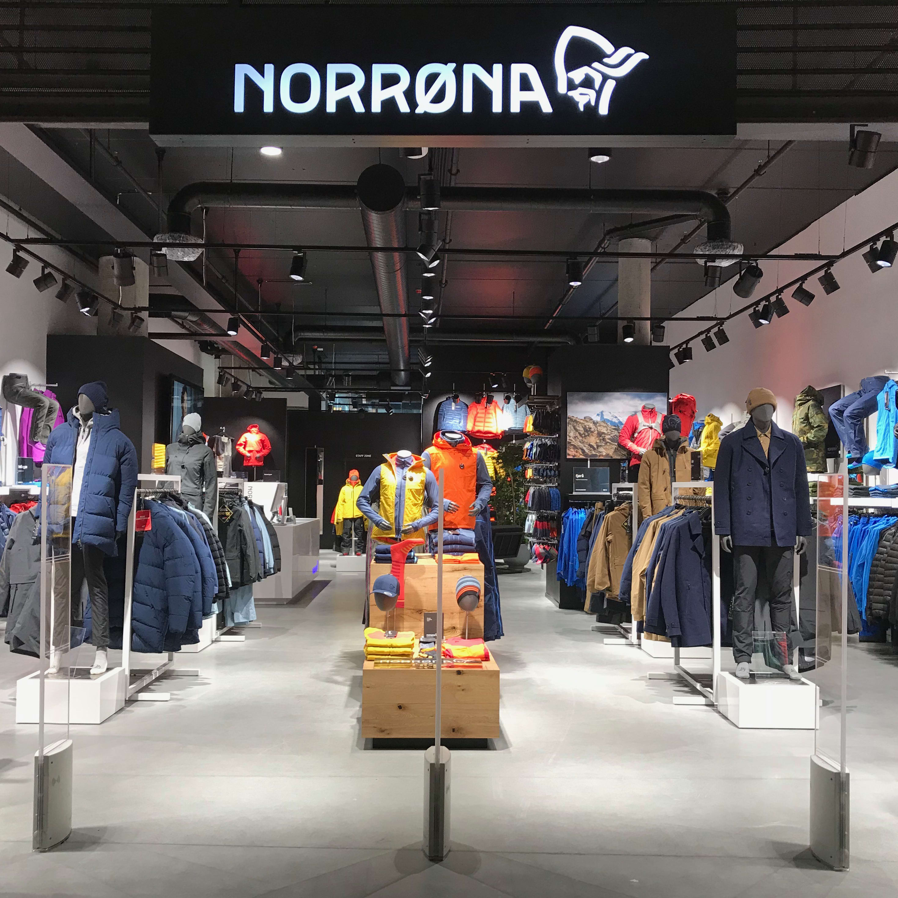 A Norrøna store interior with mannequins wearing winter clothing and clothes displayed on racks.  
