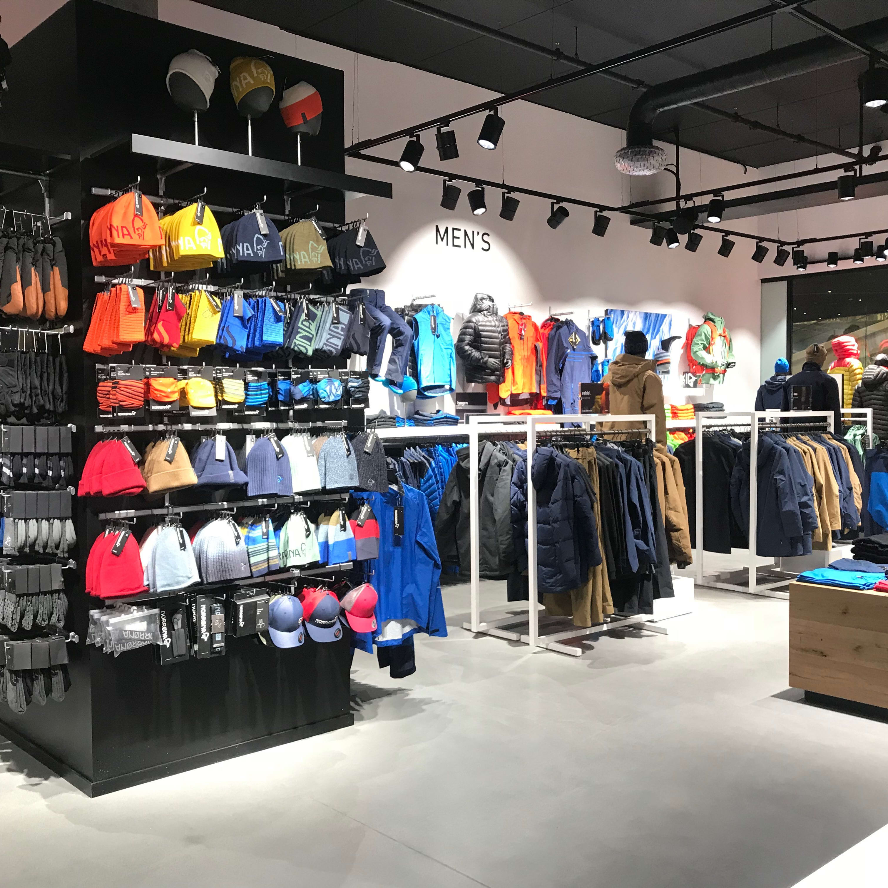 Norrøna store interior featuring displays of men's outdoor jackets, beanies, and gloves.