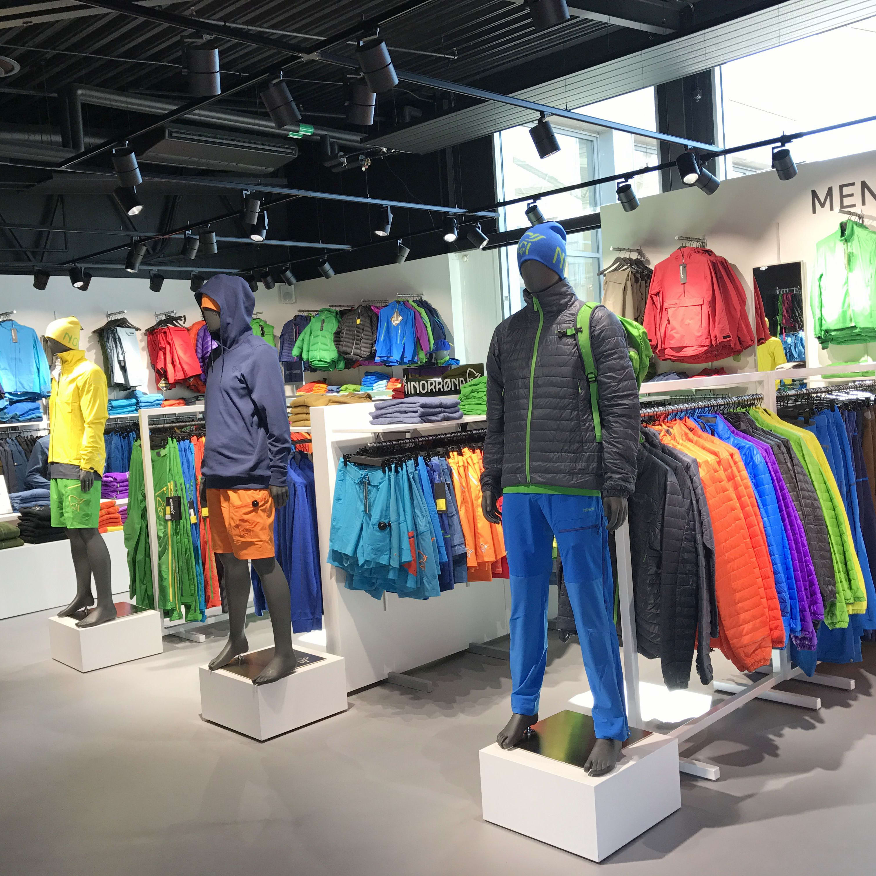 Mannequins displaying colorful Norrøna outdoor apparel on racks inside a retail store.