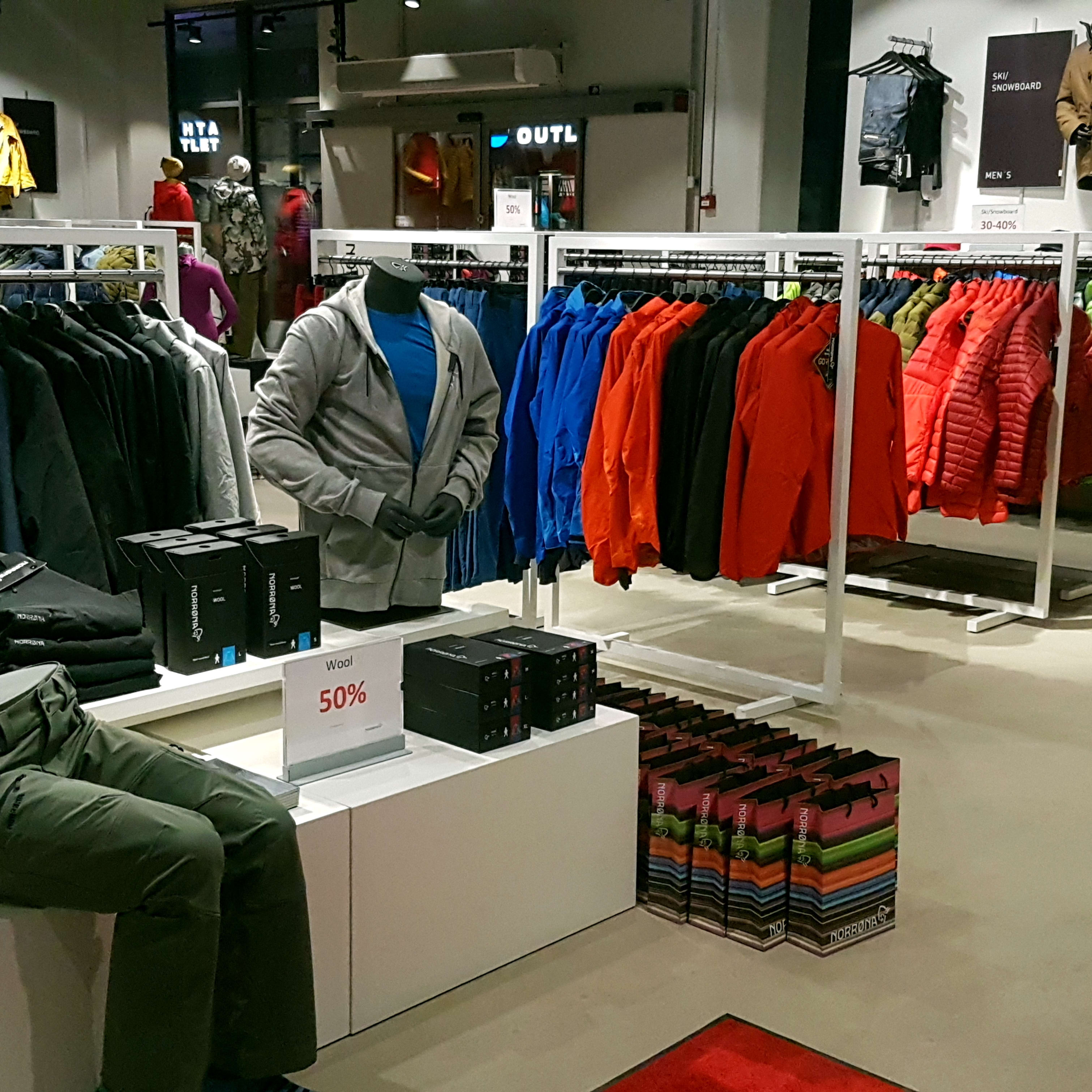 Norrøna clothing store display featuring colorful jackets, pants, and dressed mannequins.