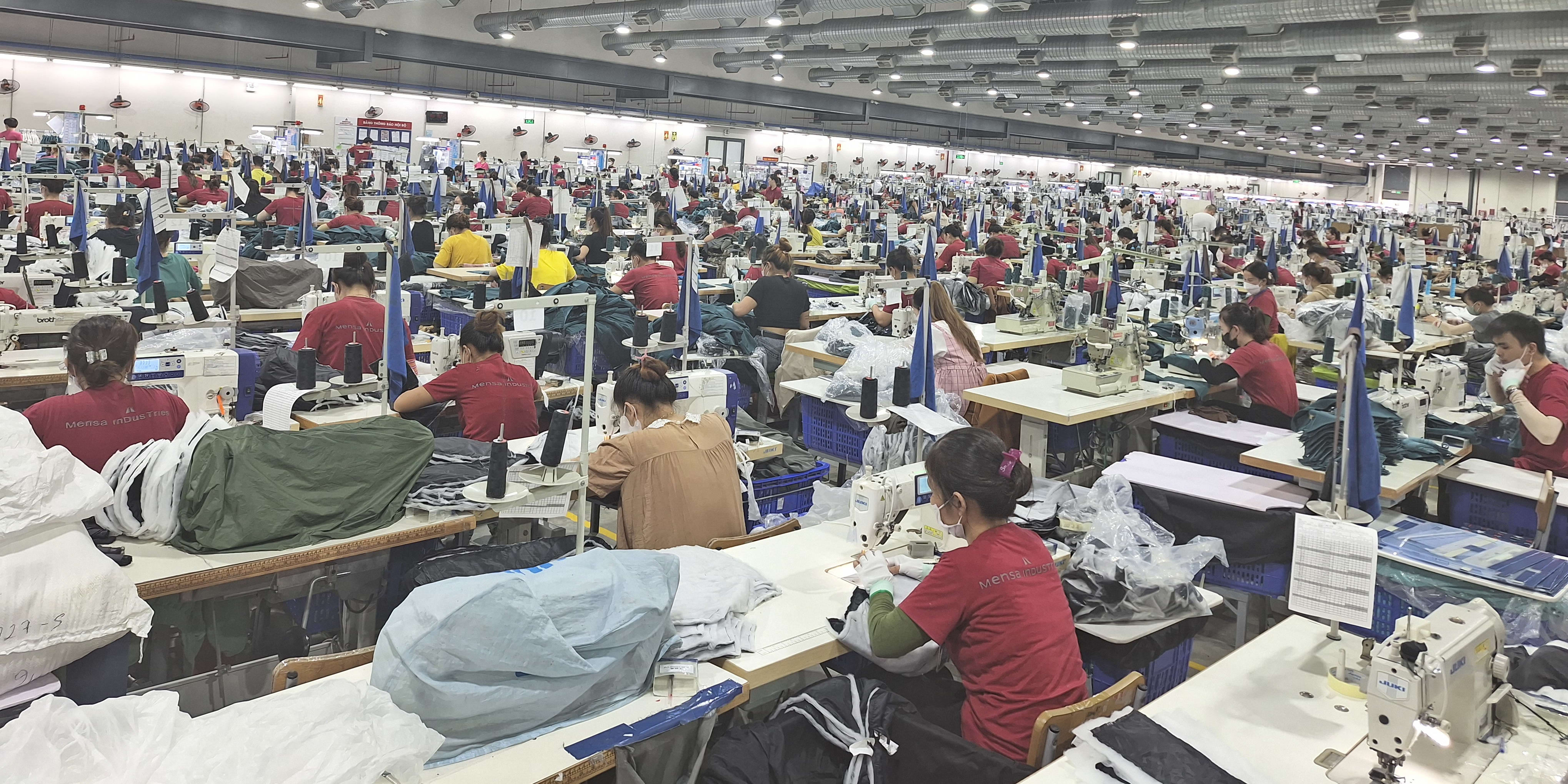 A large factory space with rows of people sewing Norrøna garments.