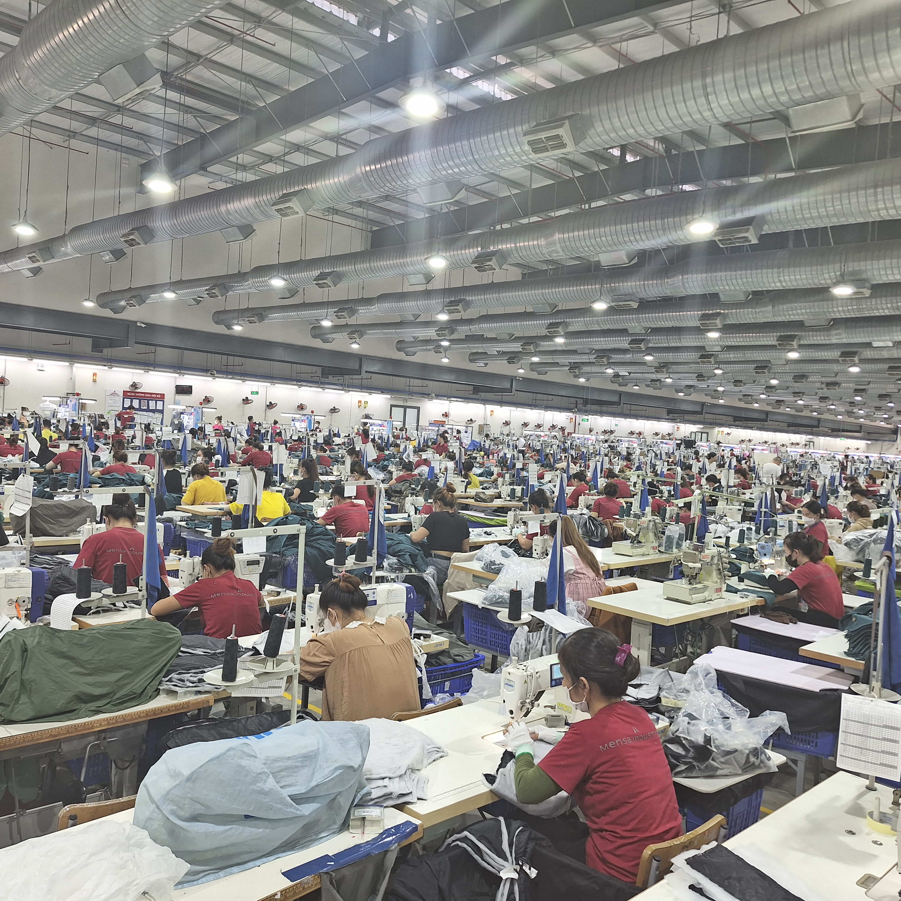 A large factory space with rows of people sewing Norrøna garments.