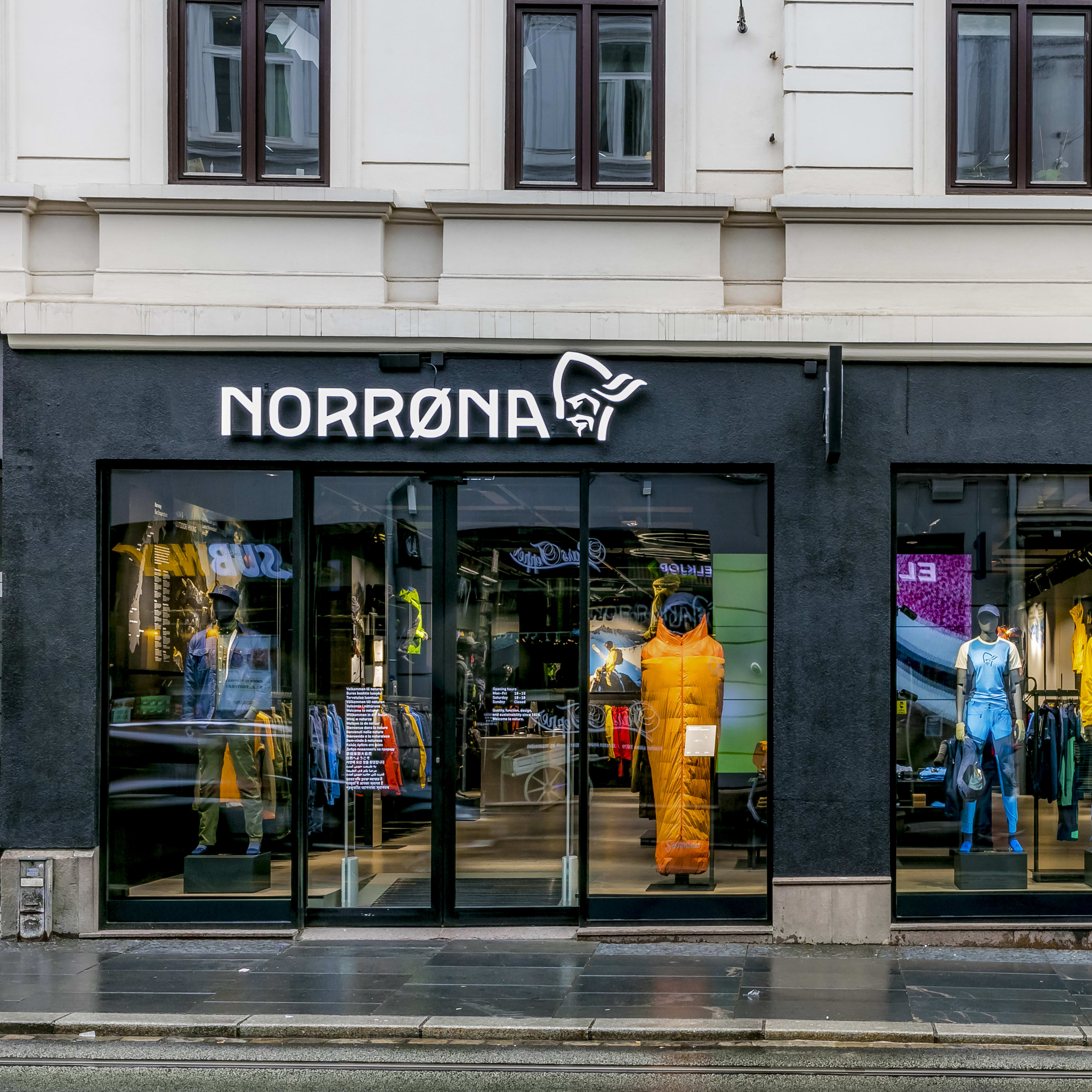 A Norrøna store storefront with mannequins wearing outdoor clothing displayed in the window. 
