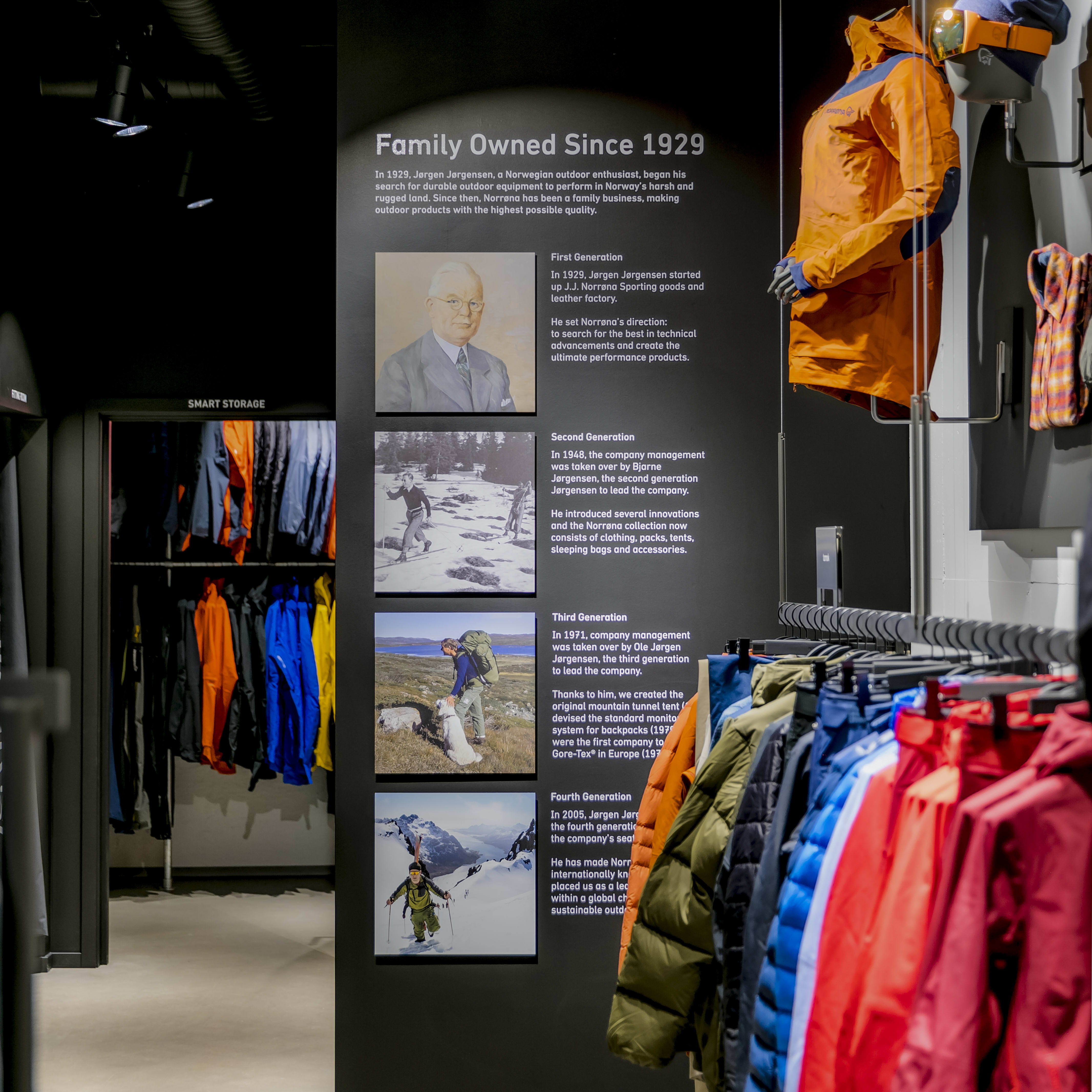 Racks of colorful Norrøna jackets displayed next to a wall detailing the brand's family history.
