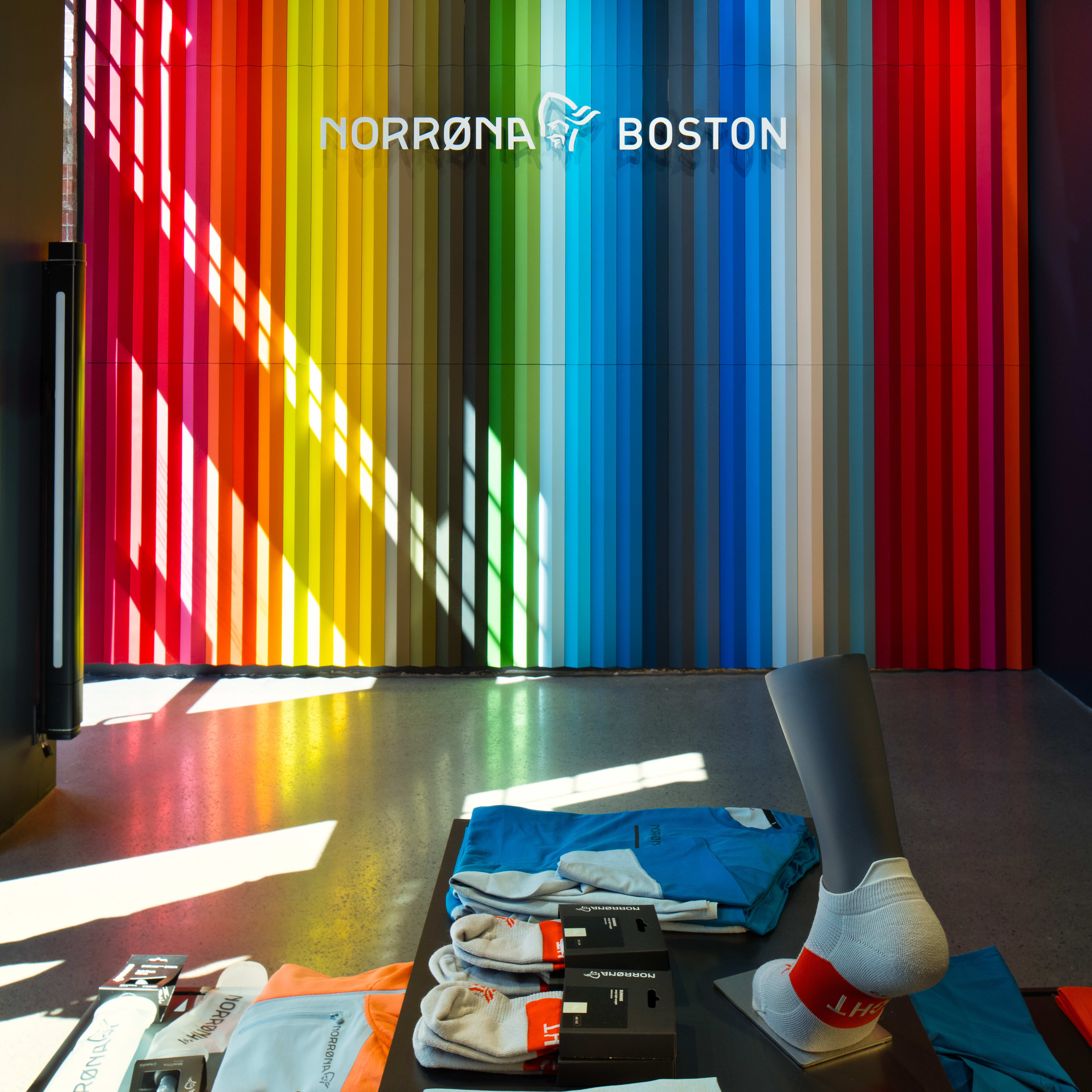 Norrøna Boston store interior with a rainbow colored wall and Norrøna apparel and socks on display. 
