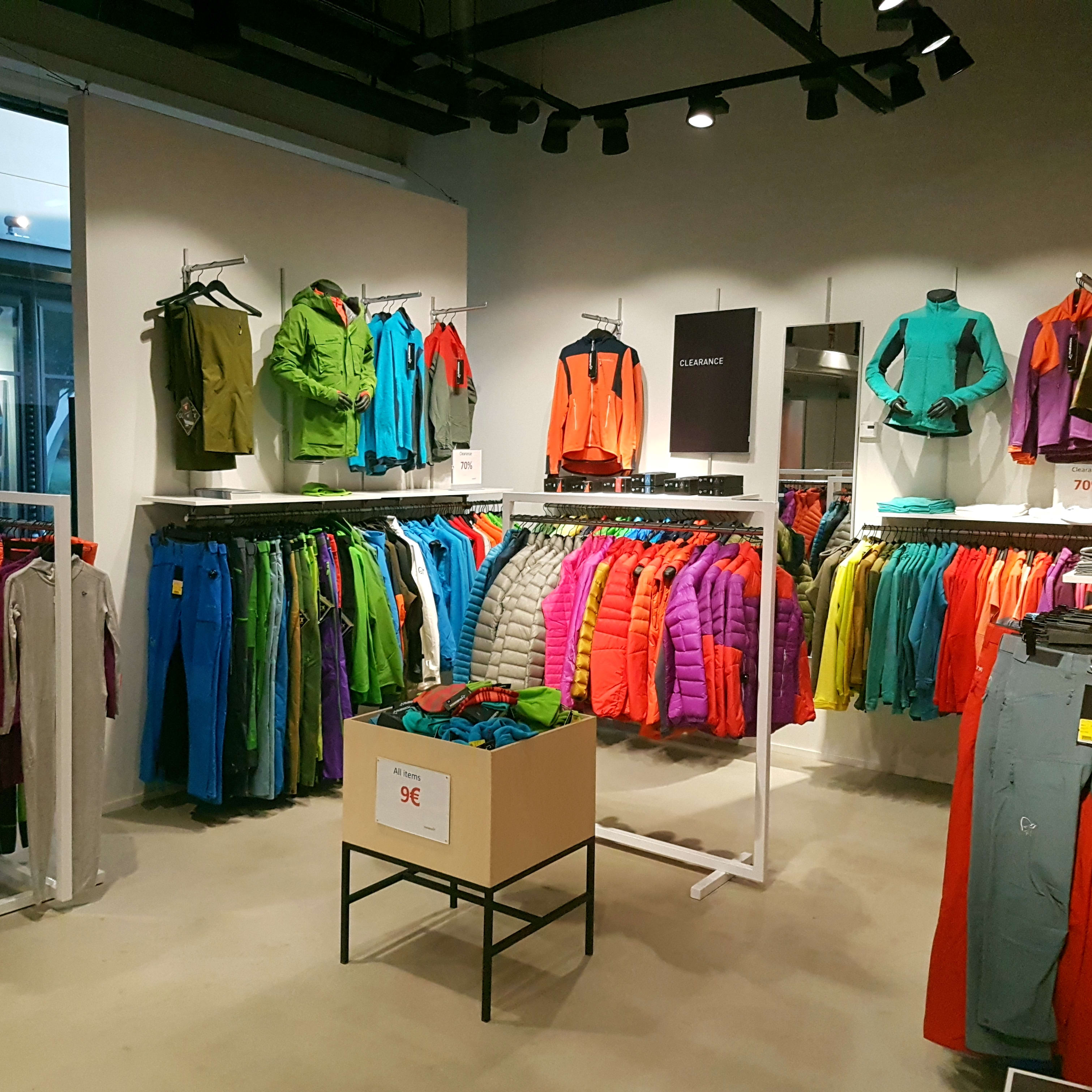 Colorful Norrøna clothing displayed on racks inside a retail store.